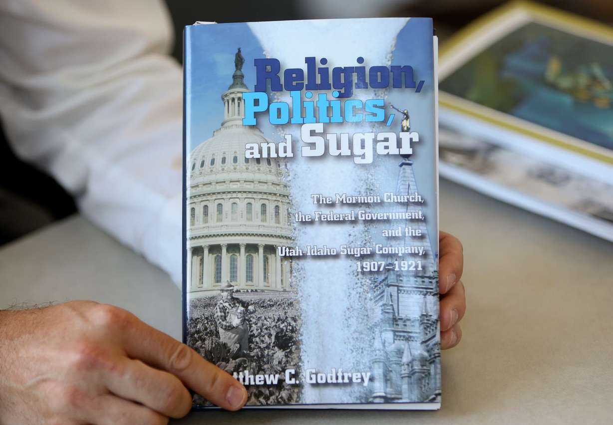 Matthew C. Godfrey, Church History Department senior managing historian of outreach and engagement, holds his book “Religion, Politics, and Sugar,” in his office at the Church History Library in Salt Lake City on Aug. 13