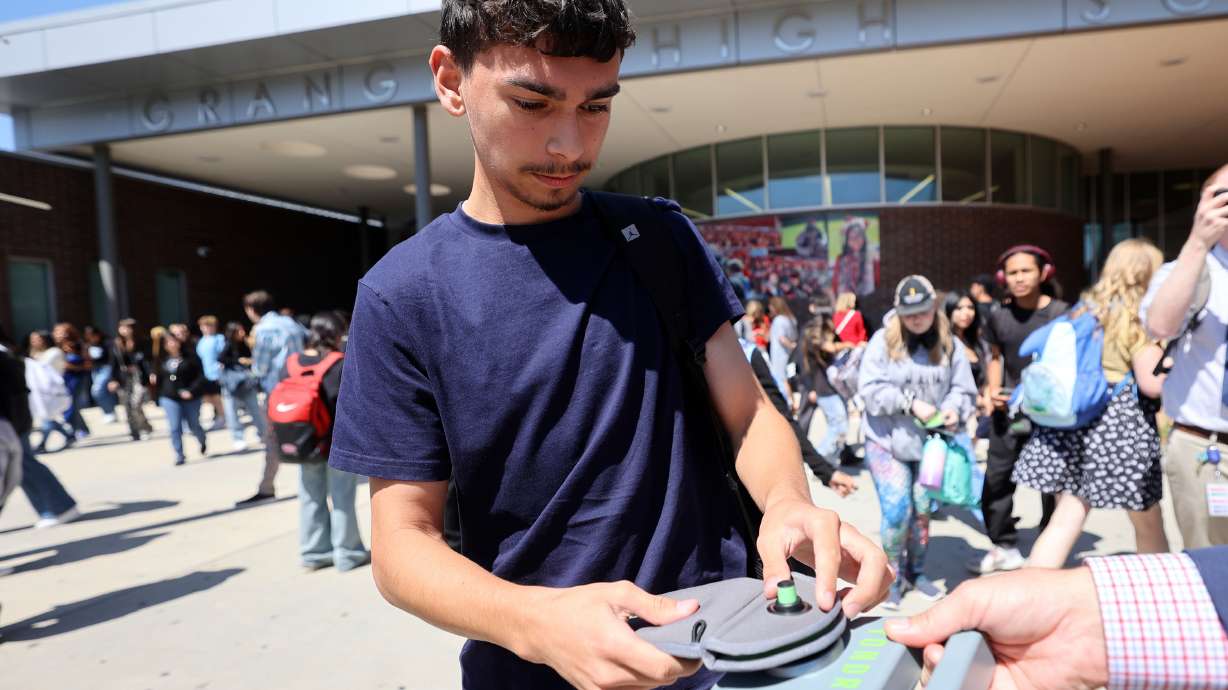 Jesse Martinez unlocks a Yondr pouch that has his cellphone inside on a magnetic unlocking base as he leaves Granger High School in West Valley City on Monday. Students lock their phones in the pouches when they arrive at the school.