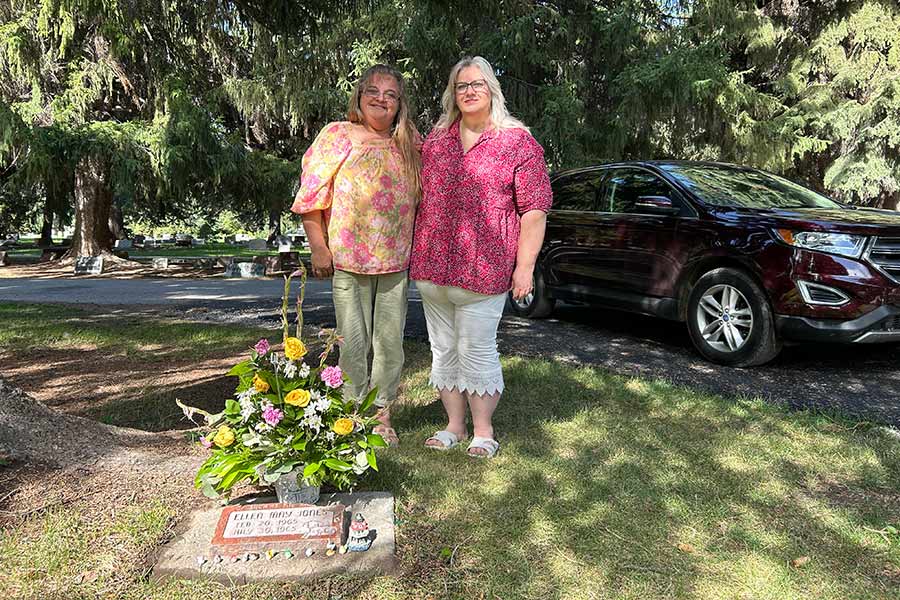 Charlene Goetz, left, and Shelley Ramey pose for a photo next to Ellen’s grave at Rose Hill Cemetery in Idaho Falls.