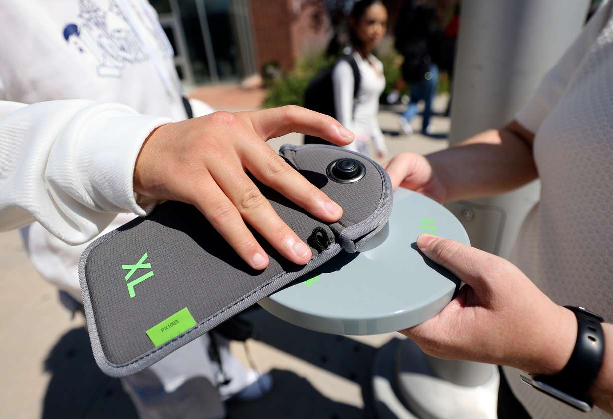 A student unlocks a Yondr pouch that has his cellphone inside on a magnetic unlocking base as he leaves Granger High School in West Valley City on Monday. Students lock their phones in the pouches when they arrive at school, creating a phone-free learning environment.