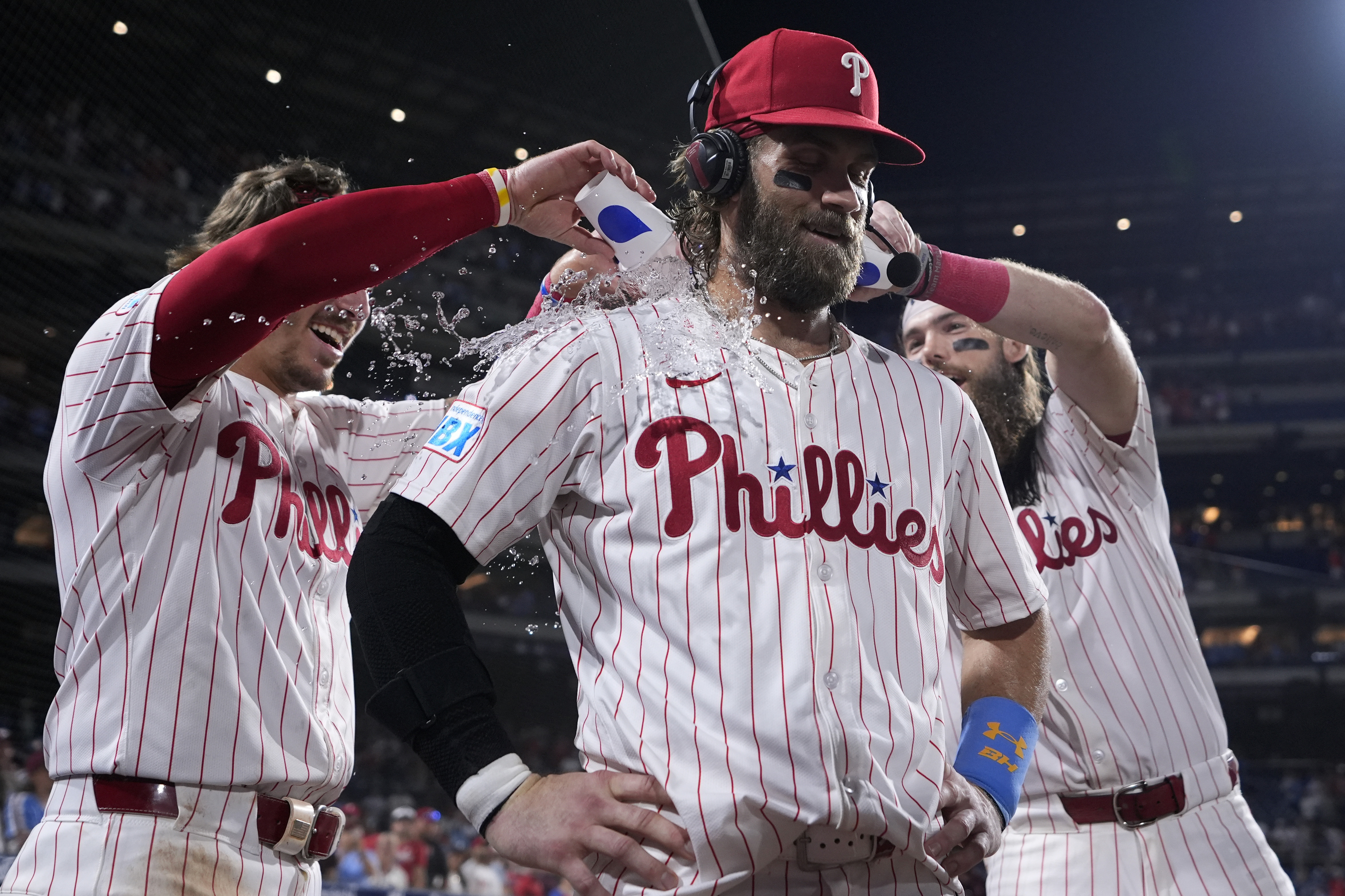 Philadelphia Phillies' Bryce Harper, center, is doused by Bryson Stott, left, and Brandon Marsh after hitting the game-winning RBI-single against Houston Astros pitcher Josh Hader during the 10th inning of a baseball game, Monday, Aug. 26, 2024, in Philadelphia. 
