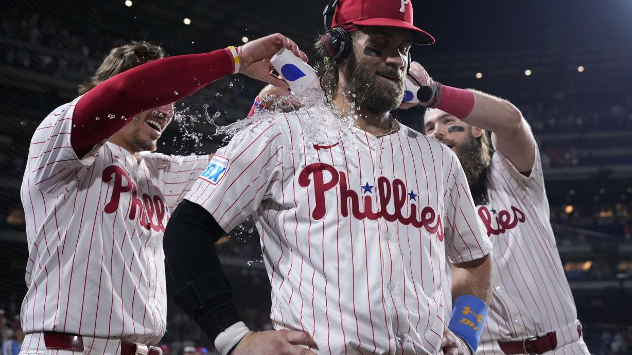 Philadelphia Phillies' Bryce Harper, center, is doused by Bryson Stott, left, and Brandon Marsh after hitting the game-winning RBI-single against Houston Astros pitcher Josh Hader during the 10th inning of a baseball game, Monday, Aug. 26, 2024, in Philadelphia.