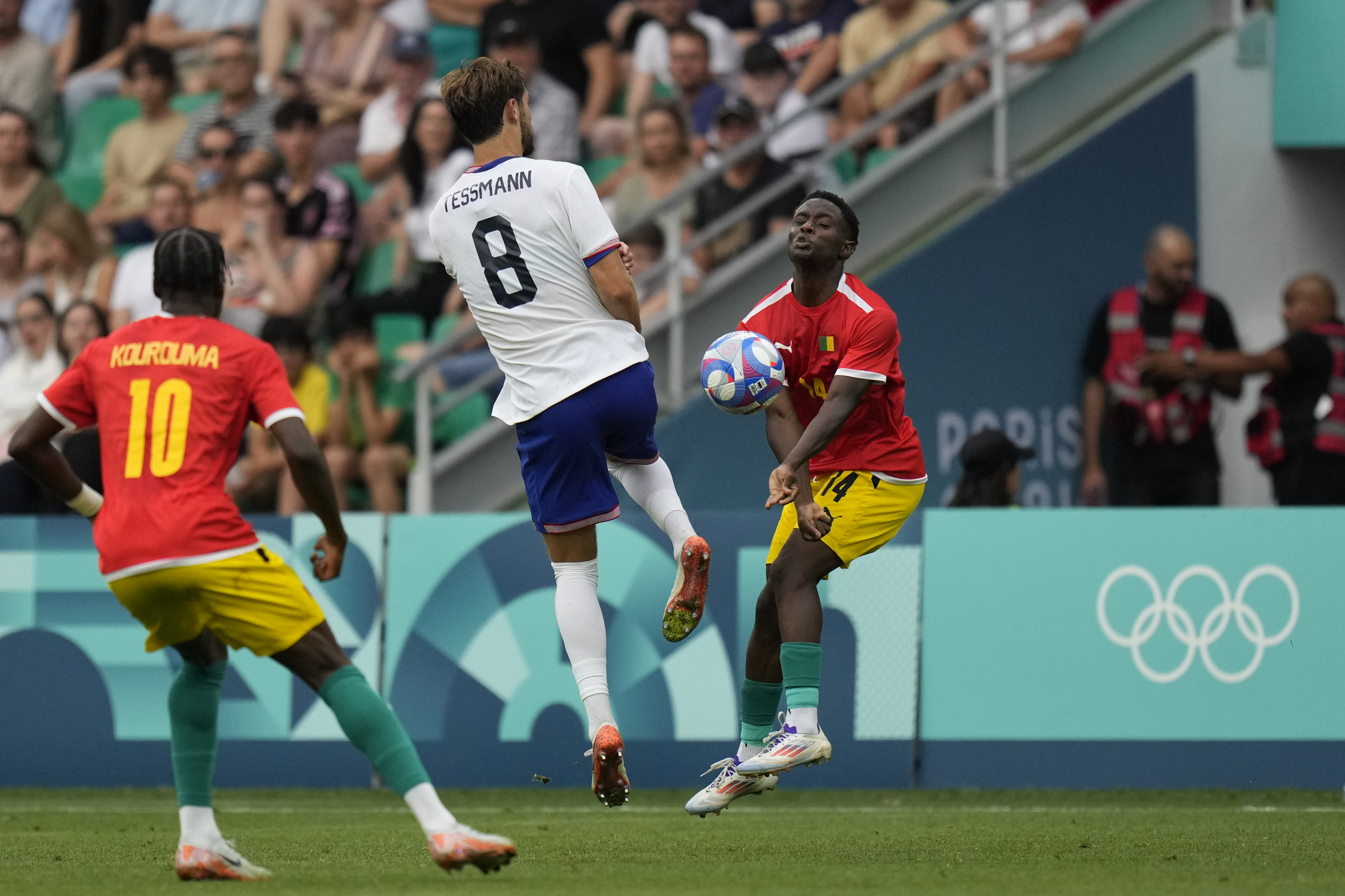 Guinea's Amadou Diallo, right, and United States' Tanner Tessmann, center, compete for the ball during the men's Group A soccer match between the United States and Guinea, at Geoffroy-Guichard Stadium, during the 2024 Summer Olympics, Tuesday, July 30, 2024, in Saint-Etienne, France. 