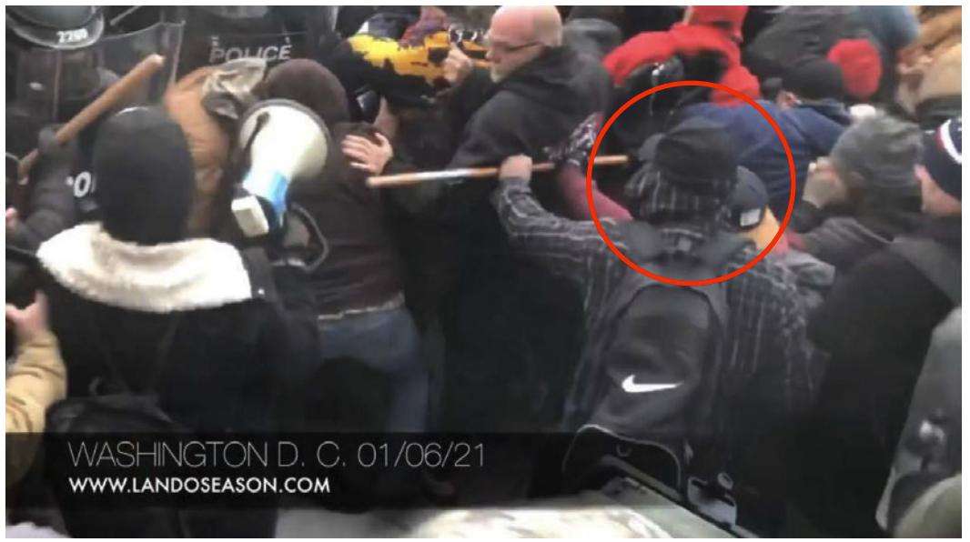 A screenshot from open-source video that prosecutors say captures Hal Ray Huddleston grabbing a flagpole and using it to push against other rioters in an effort to hold back the police line from advancing at the U.S. Capitol on Jan. 6, 2021.