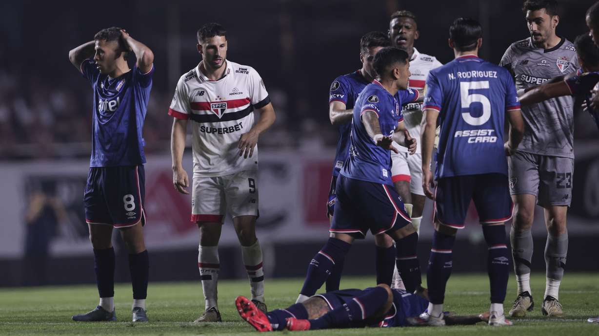 Juan Izquierdo of Uruguay's Nacional, bottom, lies on the pitch after collapsing during a Copa Libertadores soccer game against Brazil's Sao Paulo at Morumbi stadium in Sao Paulo, Thursday, Aug. 22, 2024.