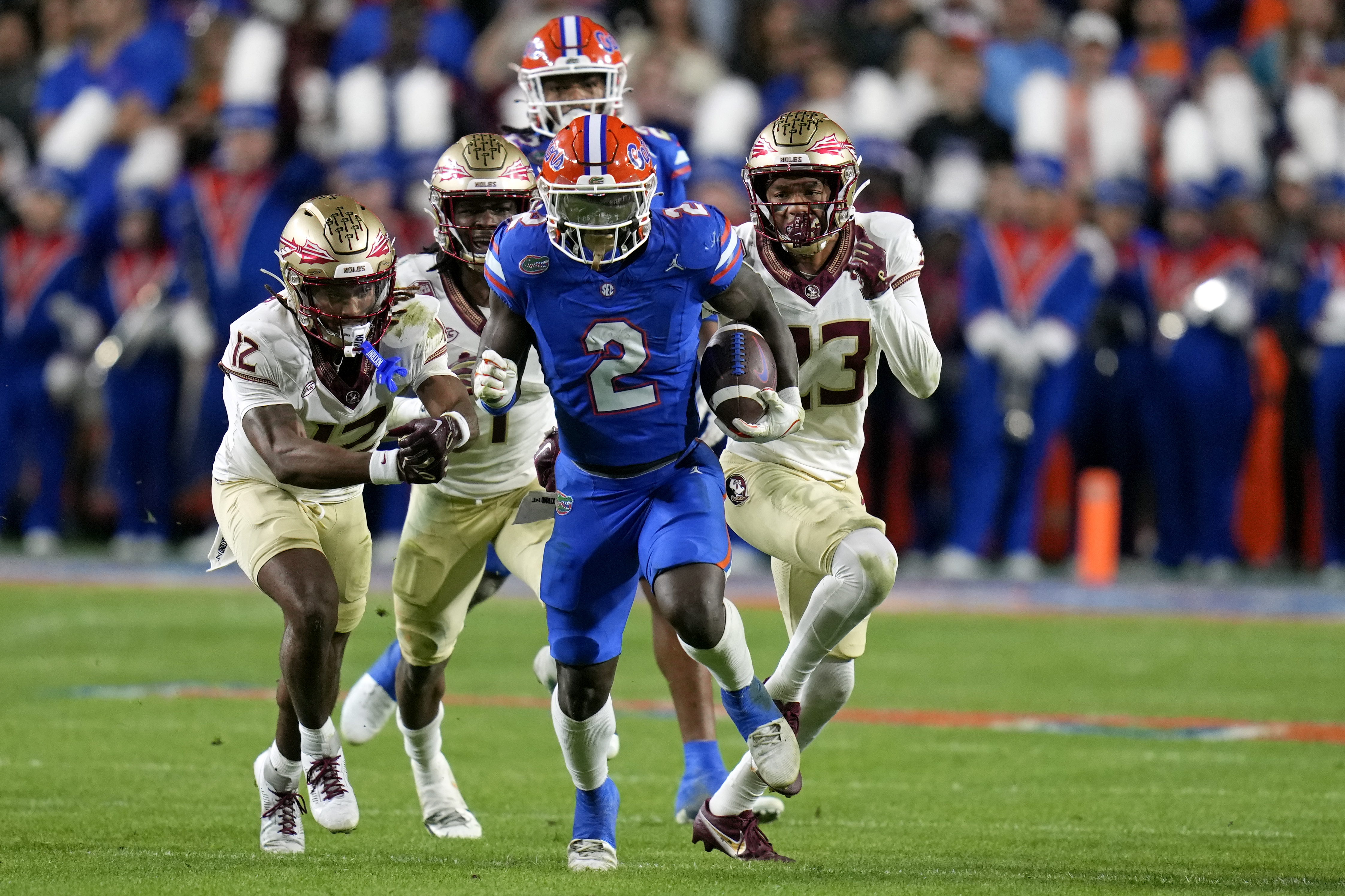 FILE - Florida running back Montrell Johnson Jr. (2) outruns Florida State defensive back Conrad Hussey (12), defensive back Akeem Dent, back center, and defensive back Fentrell Cypress II, right, on a 52-yard run during the first half of an NCAA college football game, Nov. 25, 2023, in Gainesville, Fla.