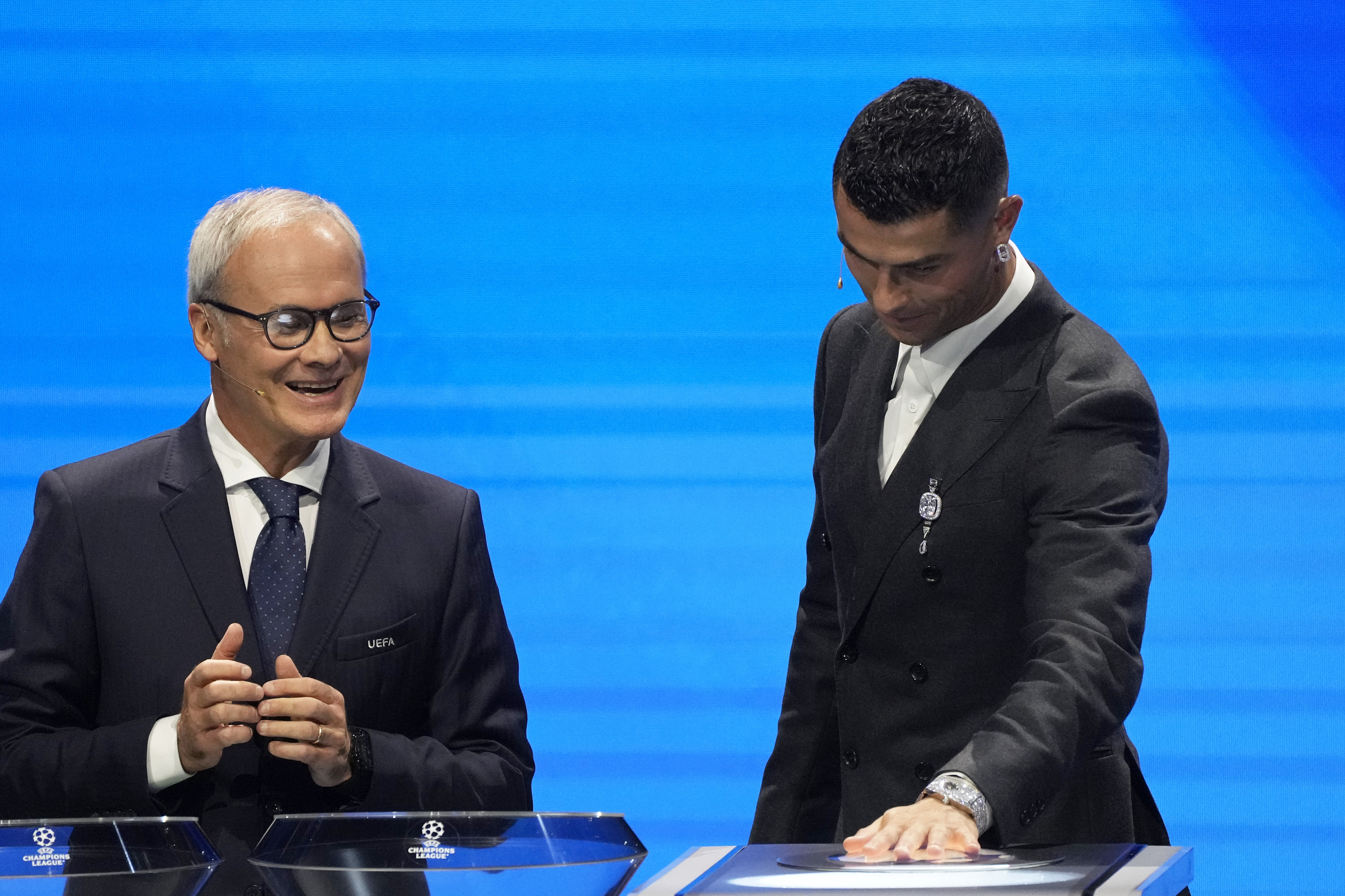 UEFA's Giorgio Marchetti watches player Cristiano Ronaldo press a button to proceed with the Champions League, league phase, draw, in Monaco, Thursday, Aug. 29, 2024. 