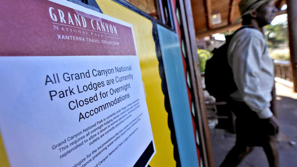 A sign denoting park lodge closures hangs on the door as a guest exits the Bright Angel Lodge, Thursday in Grand Canyon, Ariz.