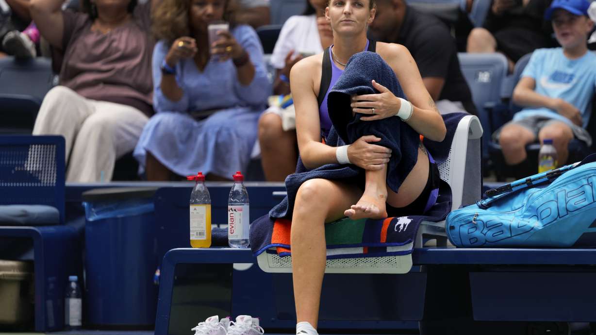Karolina Pliskova, of the Czech Republic, checks her ankle before retiring against Jasmine Paolini, of Italy, during the second round of the U.S. Open tennis championships, Thursday, Aug. 29, 2024, in New York.