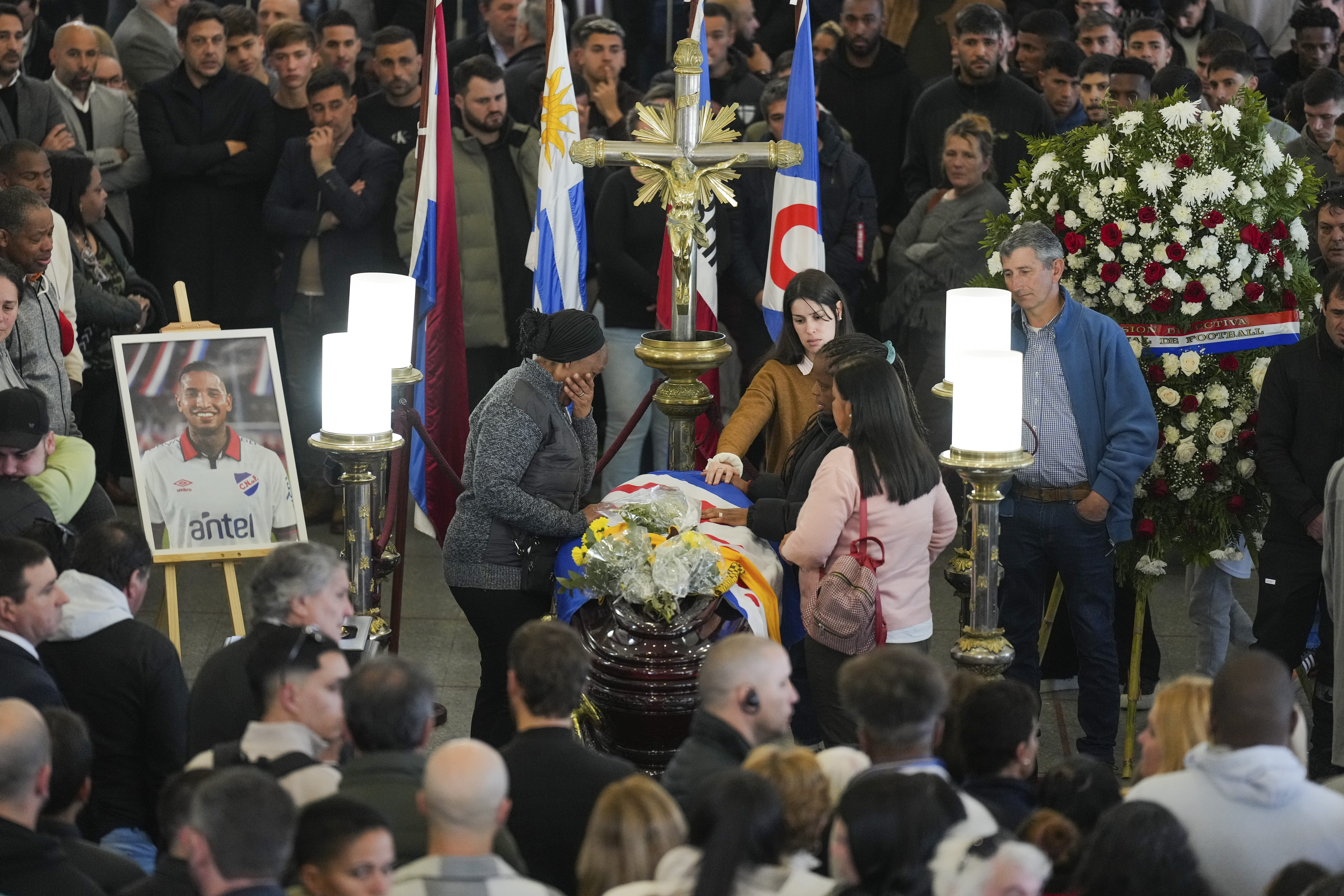 Family members of soccer player Juan Izquierdo stand by his coffin during a wake at his Nacional soccer club in Montevideo, Uruguay, Thursday, Aug. 29, 2024. Izquierdo died at a Brazilian hospital after collapsing on Aug. 22 during a Copa Libertadores soccer match between Nacional and Sao Paulo. 