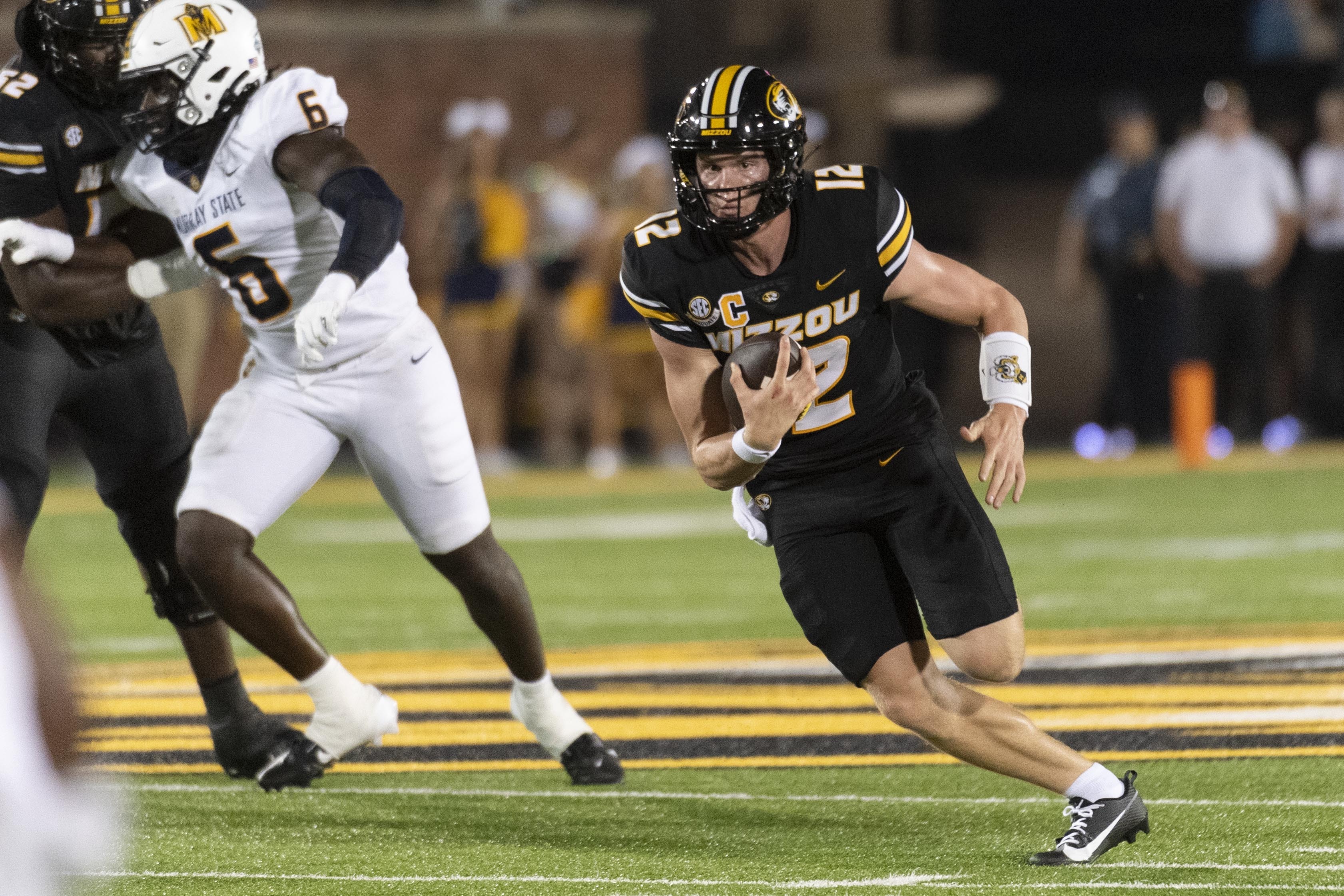 Missouri quarterback Brady Cook, right, runs past Murray State defensive lineman Kevon Haigler (6) during the first half of an NCAA college football game Thursday, Aug. 29, 2024, in Columbia, Mo. 