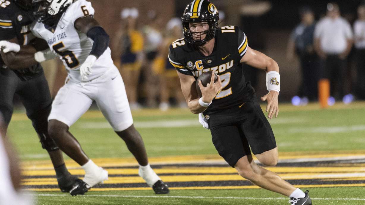 Missouri quarterback Brady Cook, right, runs past Murray State defensive lineman Kevon Haigler (6) during the first half of an NCAA college football game Thursday, Aug. 29, 2024, in Columbia, Mo.