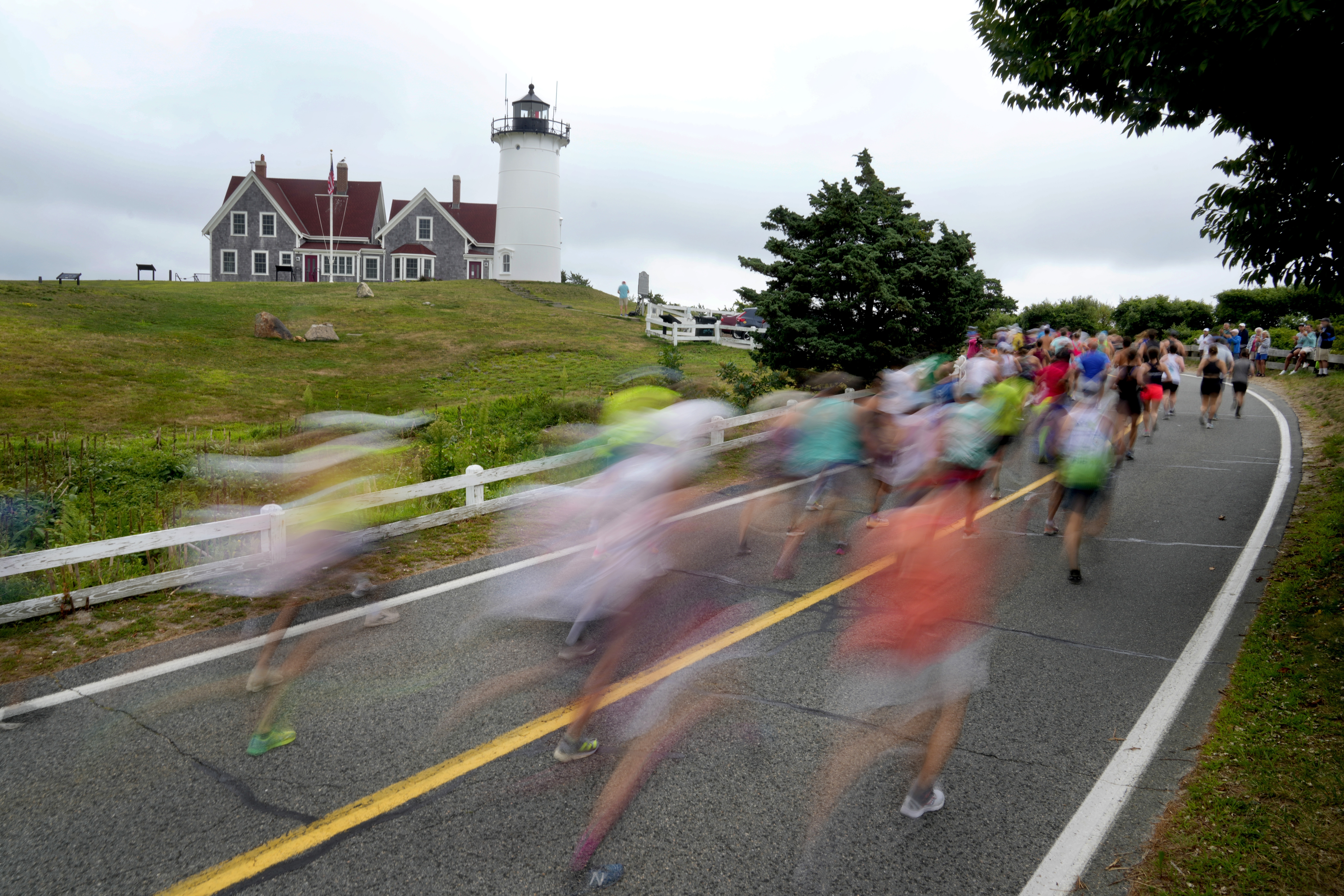 Runners pass Nobska Lighthouse near the 1-mile mark of the Falmouth Road Race, Sunday, Aug. 18, 2024, in Falmouth, Mass. 