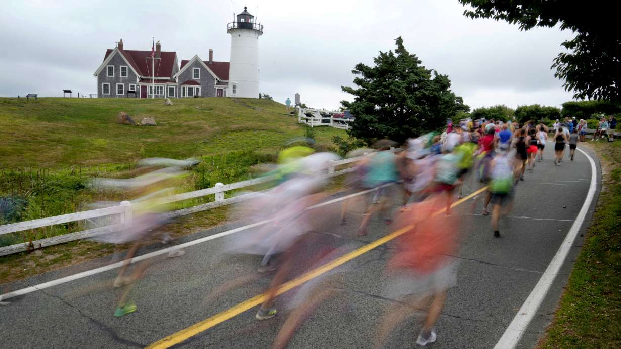 Runners pass Nobska Lighthouse near the 1-mile mark of the Falmouth Road Race, Sunday, Aug. 18, 2024, in Falmouth, Mass.