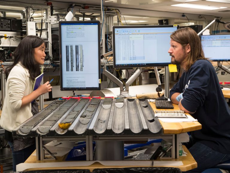 Dustin Harper, right, a University of Utah geoscientist, discusses drilling cores with colleague Weimu Xu of the University College Dublin aboard a research vessel operated by the International Ocean Discovery Program.