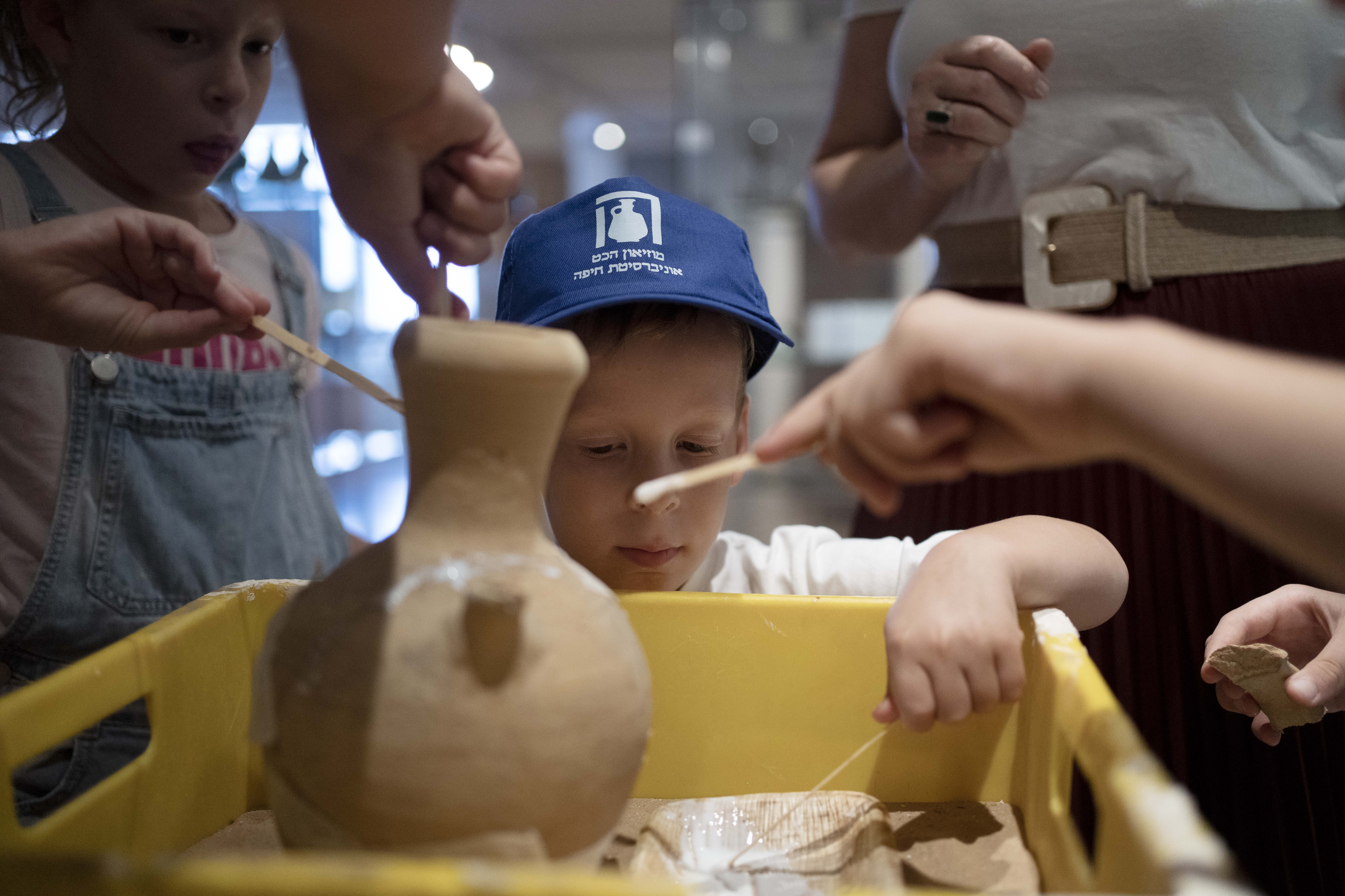 Ariel Heller, 4, helps to glue a broken clay jar during a special tour with his family after he accidentally broke another jar at the Reuben and Edith Hecht Museum in Haifa, Israel, Friday.