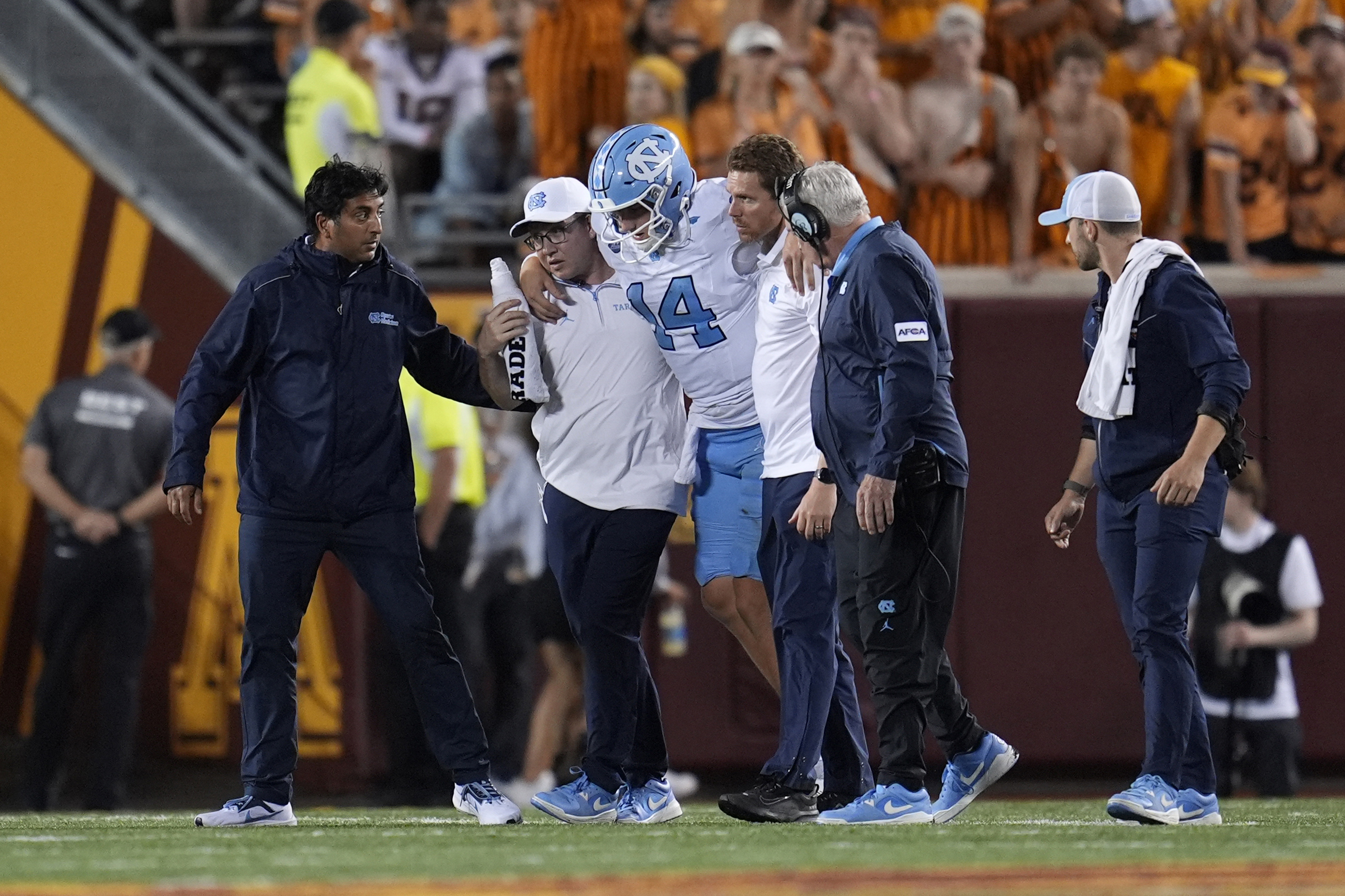 North Carolina quarterback Max Johnson (14) is helped off the field after an injury during the second half of an NCAA college football game against Minnesota, Thursday, Aug. 29, 2024, in Minneapolis.