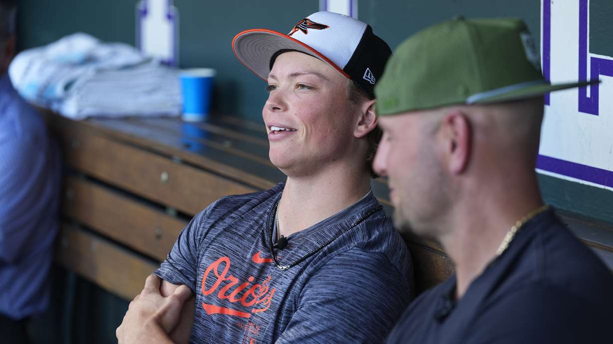 Retired Major League Baseball player Matt Holliday, front, listens as his son, Jackson, second baseman for the Baltimore Orioles, talks to reporters before the Orioles face the Colorado Rockies in a baseball game Friday, Aug. 30, 2024, in Denver.