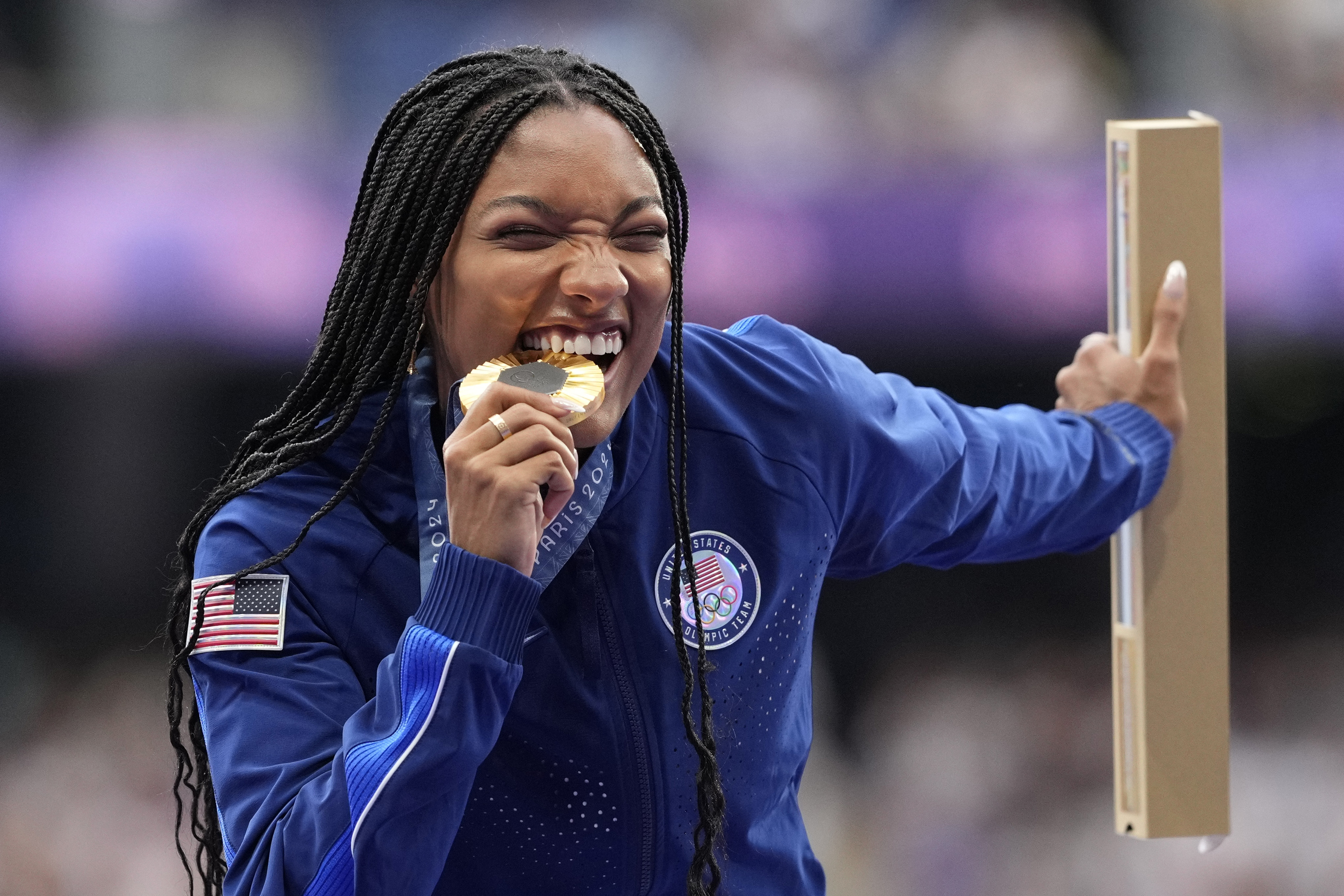 Women's long jump gold medalist Tara Davis-Woodhall, of the United States, bites into her medal on the podium at the 2024 Summer Olympics, Friday, Aug. 9, 2024, in Saint-Denis, France.