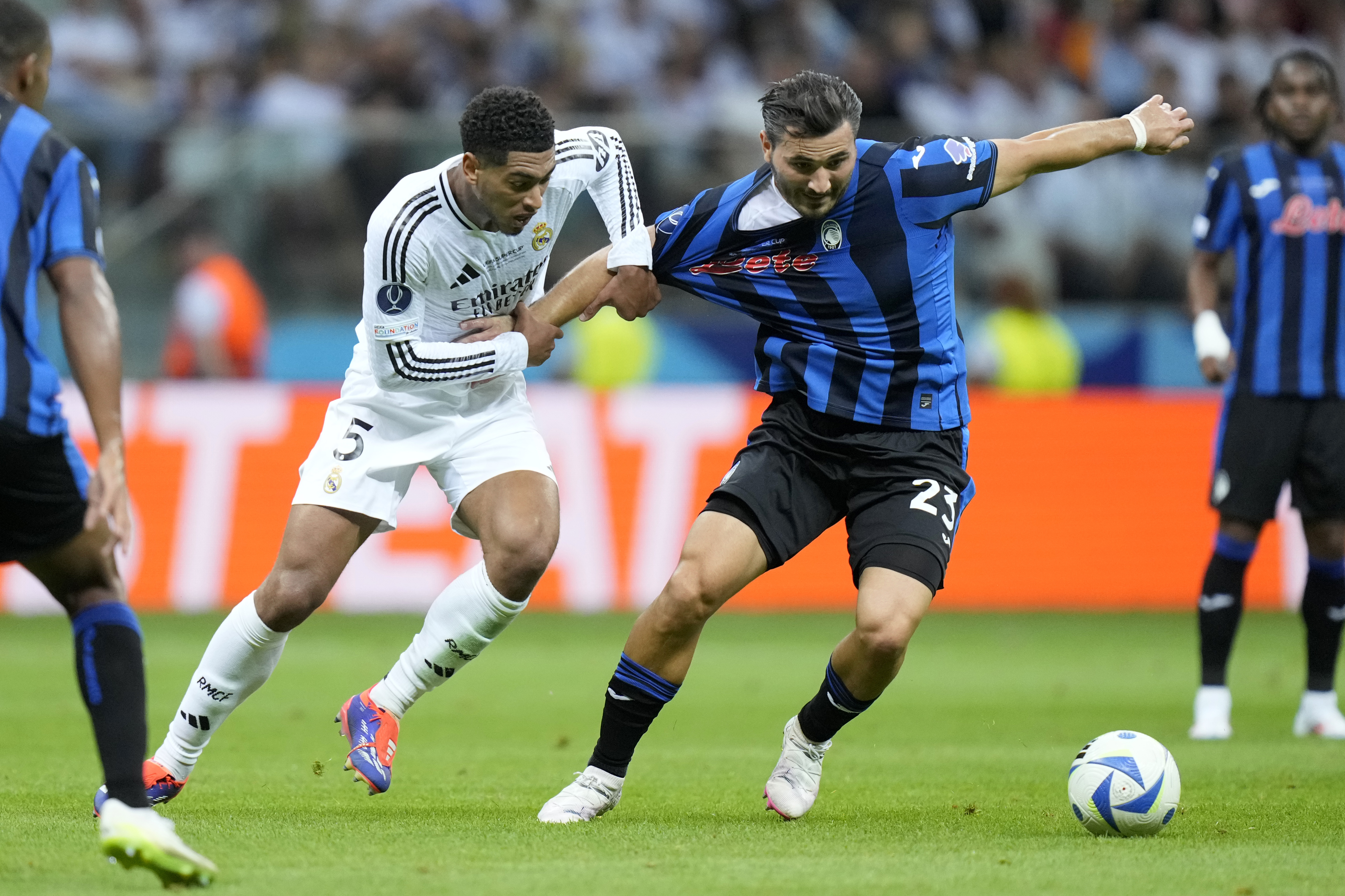 Real Madrid's Jude Bellingham, center left, fights for the ball with Atalanta's Sead Kolasinac during the UEFA Super Cup Final soccer match between Real Madrid and Atalanta at the Narodowy stadium in Warsaw, Poland, Wednesday, Aug. 14, 2024.