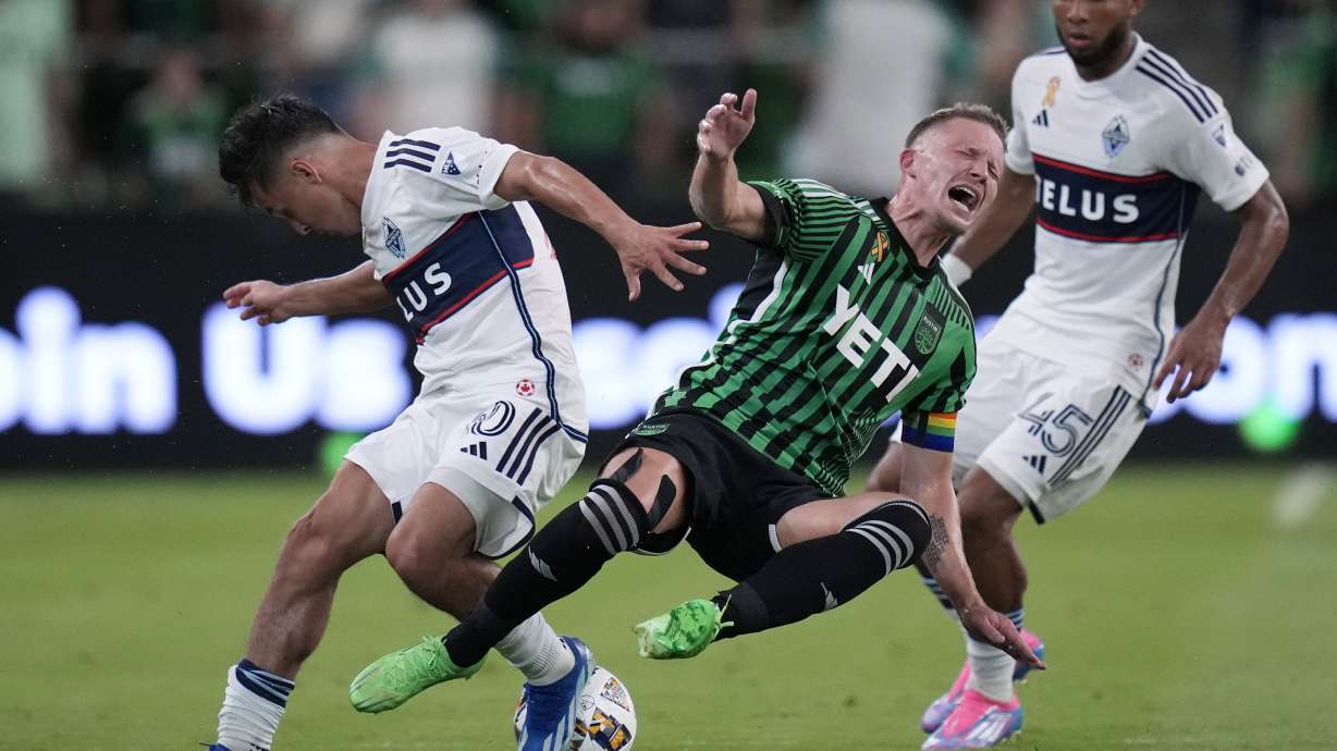 Austin FC midfielder Alexander Ring, center, is tripped as he and Vancouver Whitecaps midfielder Andres Cubas, left, compete for the ball during the first half of an MLS soccer match in Austin, Texas, Saturday, Aug. 31, 2024.