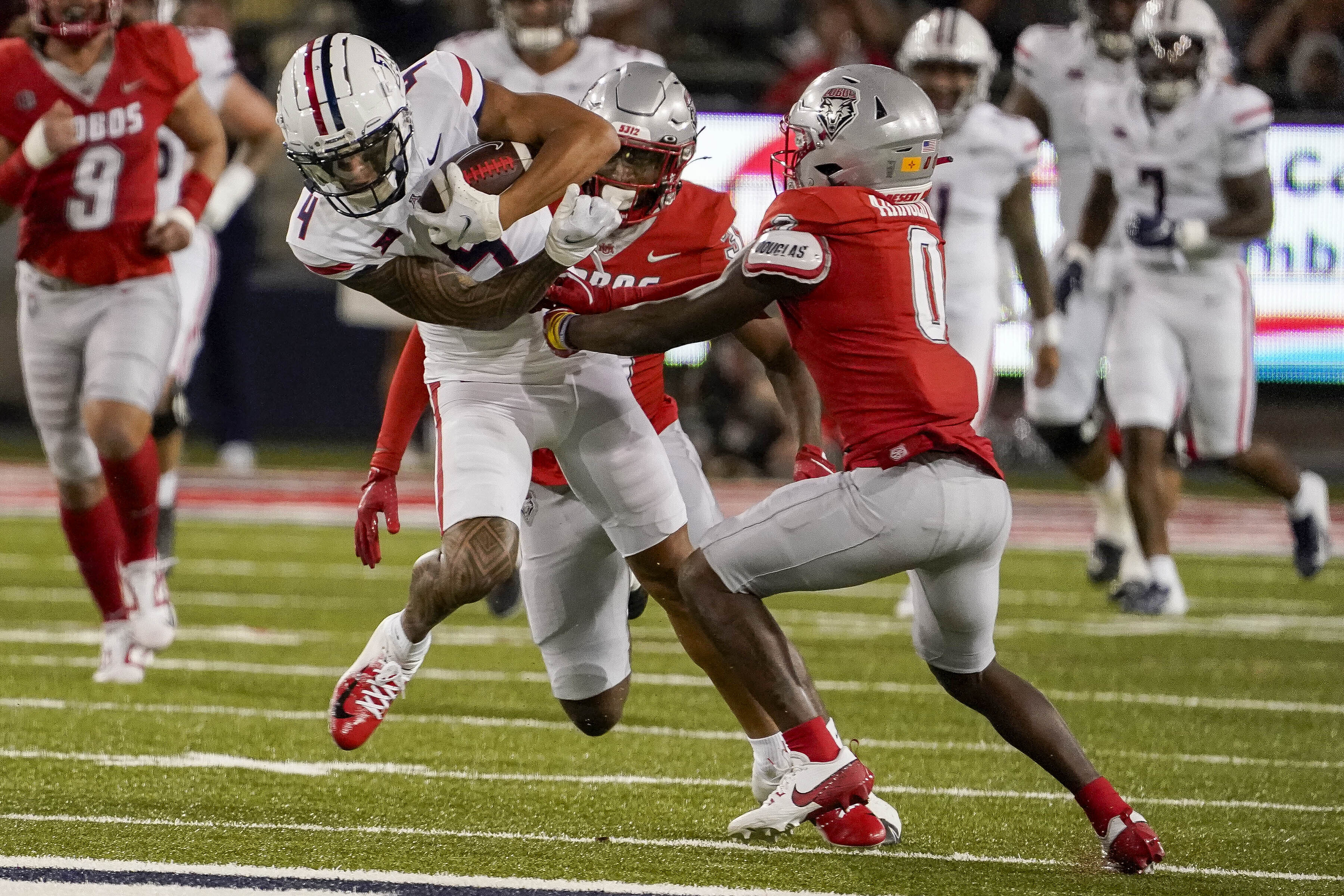 Arizona wide receiver Tetairoa McMillan (4) tries to break a tackle from New Mexico cornerback Bobby Arnold III (0) during the first half of an NCAA college football game Saturday, Aug. 31, 2024, in Tucson, Ariz. 