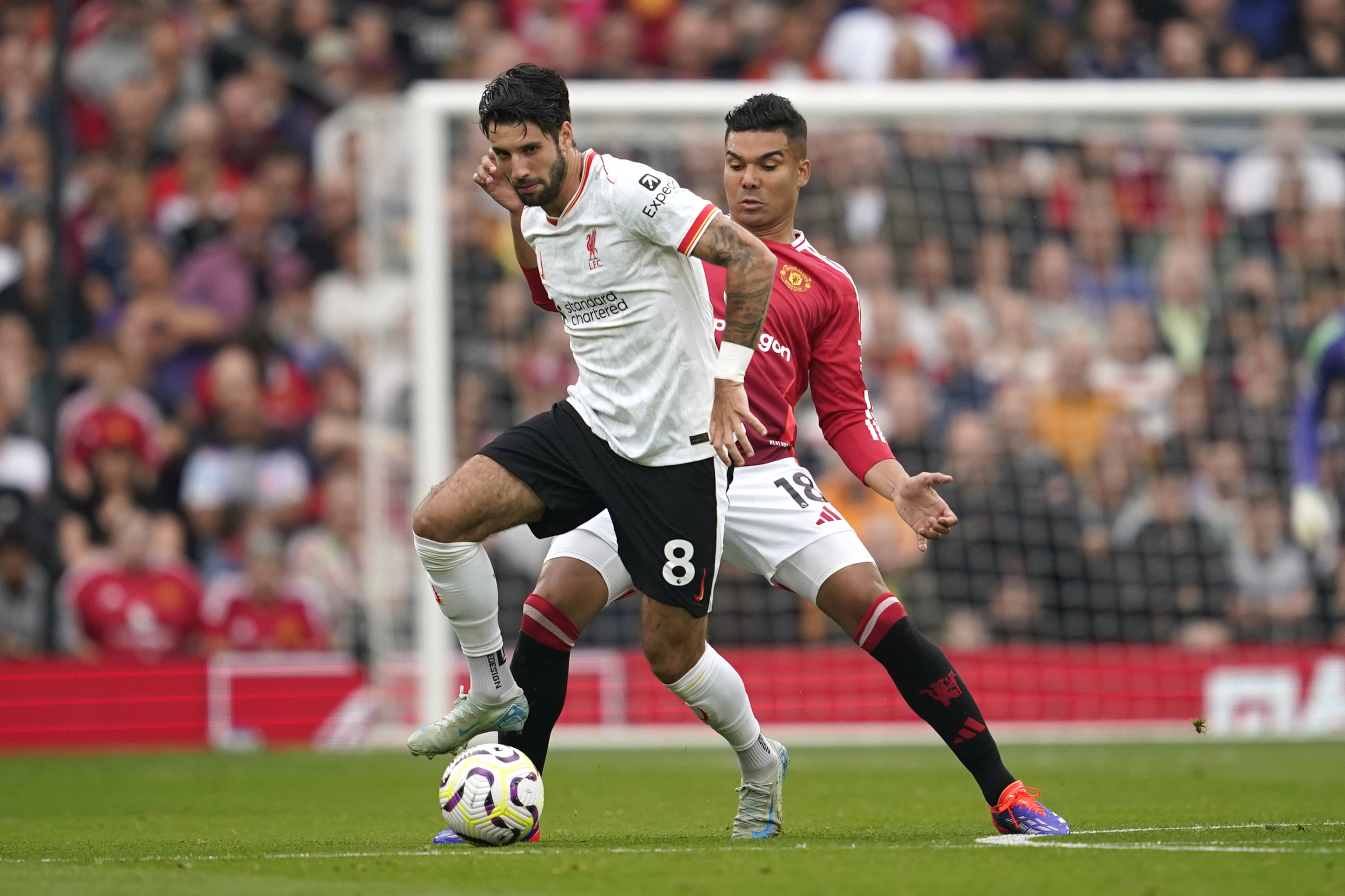 Liverpool's Dominik Szoboszlai, left, challenges for the ball with Manchester United's Casemiro during the English Premier League soccer match between Manchester United and Liverpool at Old Trafford, Sunday, Sept. 1, 2024, in Manchester, England. 
