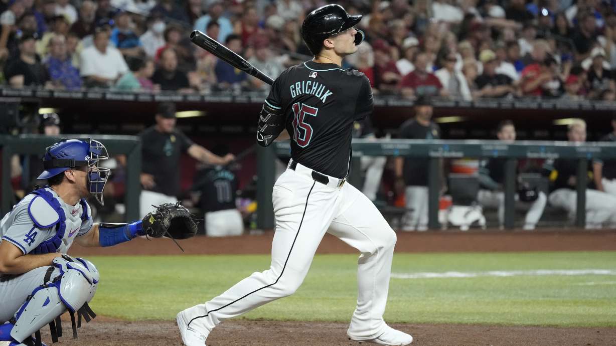 Arizona Diamondbacks' Randal Grichuk, right, watches the flight of his three-run home run as Los Angeles Dodgers catcher Austin Barnes, left, looks on during the second inning of a baseball game Sunday, Sept. 1, 2024, in Phoenix.