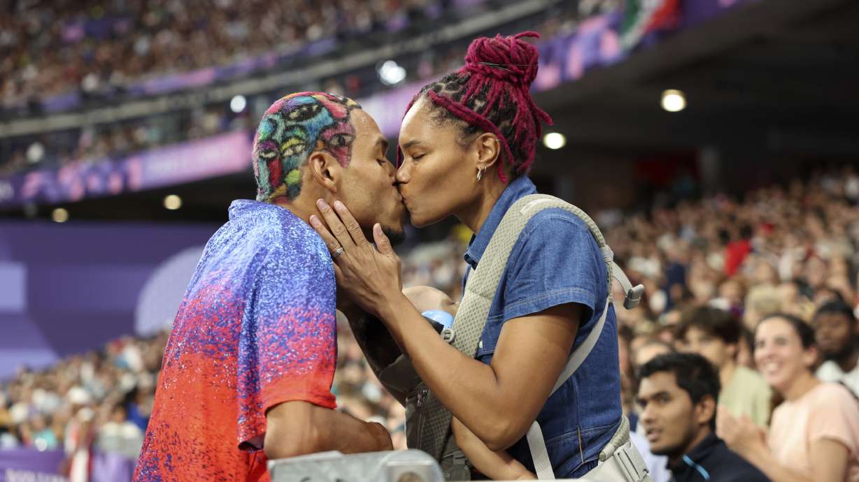 Roderick Townsend of the United States kisses his wife Tynita Townsend, with their son Rodney Townsend, between Rodrick's jumps in the T47 Men's High Jump at the 2024 Paralympics, Sunday, Sept. 1, 2024 in Paris, France.