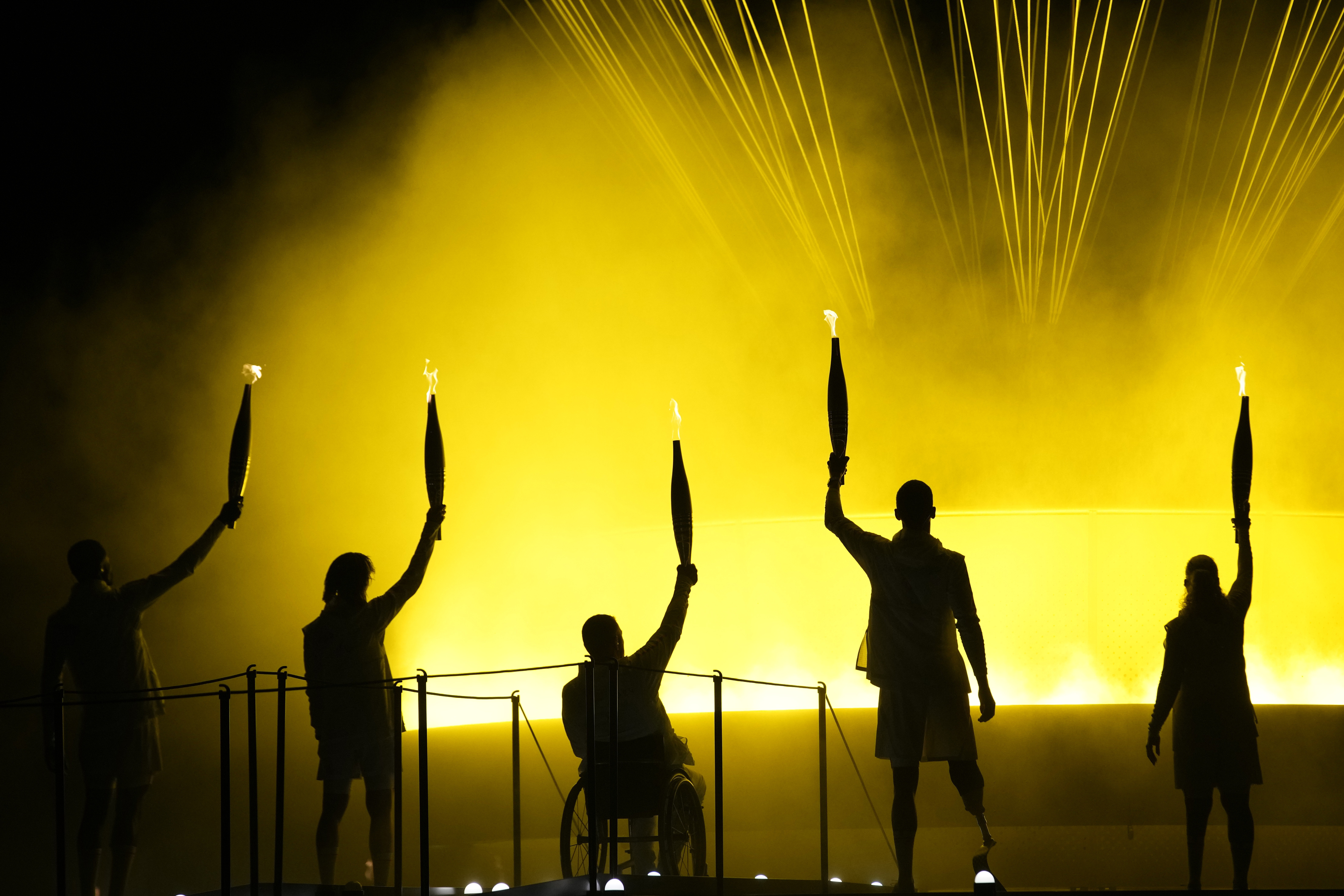 Athletes Charles-Antoine Kouakou, Nantenin Keita, Fabien Lamirault, Alexis Hanquinquant and Elodie Lorandi hold up their torches after lighting the cauldron at the Paralympics Opening Ceremony in Paris, Aug. 28, 2024. 