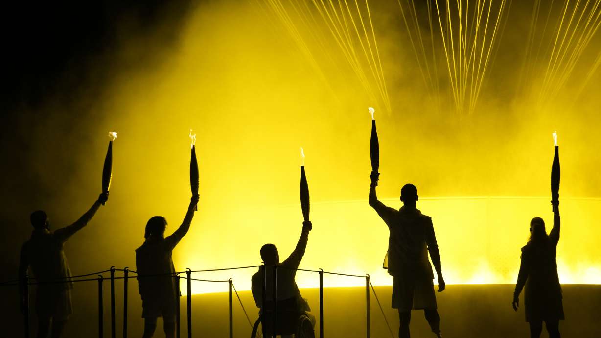 Athletes Charles-Antoine Kouakou, Nantenin Keita, Fabien Lamirault, Alexis Hanquinquant and Elodie Lorandi hold up their torches after lighting the cauldron at the Paralympics Opening Ceremony in Paris, Aug. 28, 2024.