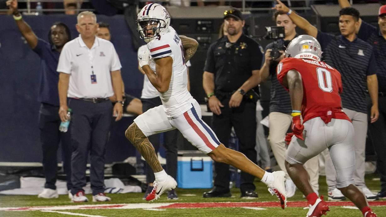 Arizona wide receiver Tetairoa McMillan, left, scores a touchdown as New Mexico cornerback Bobby Arnold III (0) pursues during the second half of an NCAA college football game Saturday, Aug. 31, 2024, in Tucson, Ariz.