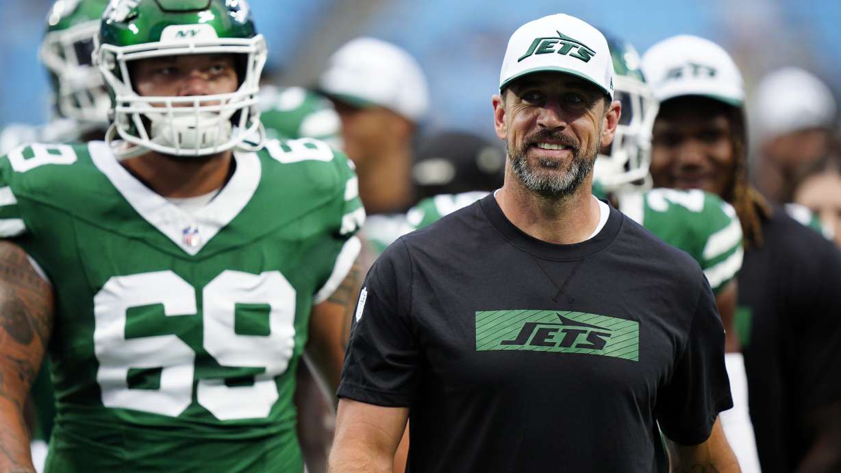 New York Jets quarterback Aaron Rodgers, right, walks on the field with teammates before a preseason NFL football game against the Carolina Panthers, Saturday, Aug. 17, 2024, in Charlotte, N.C.
