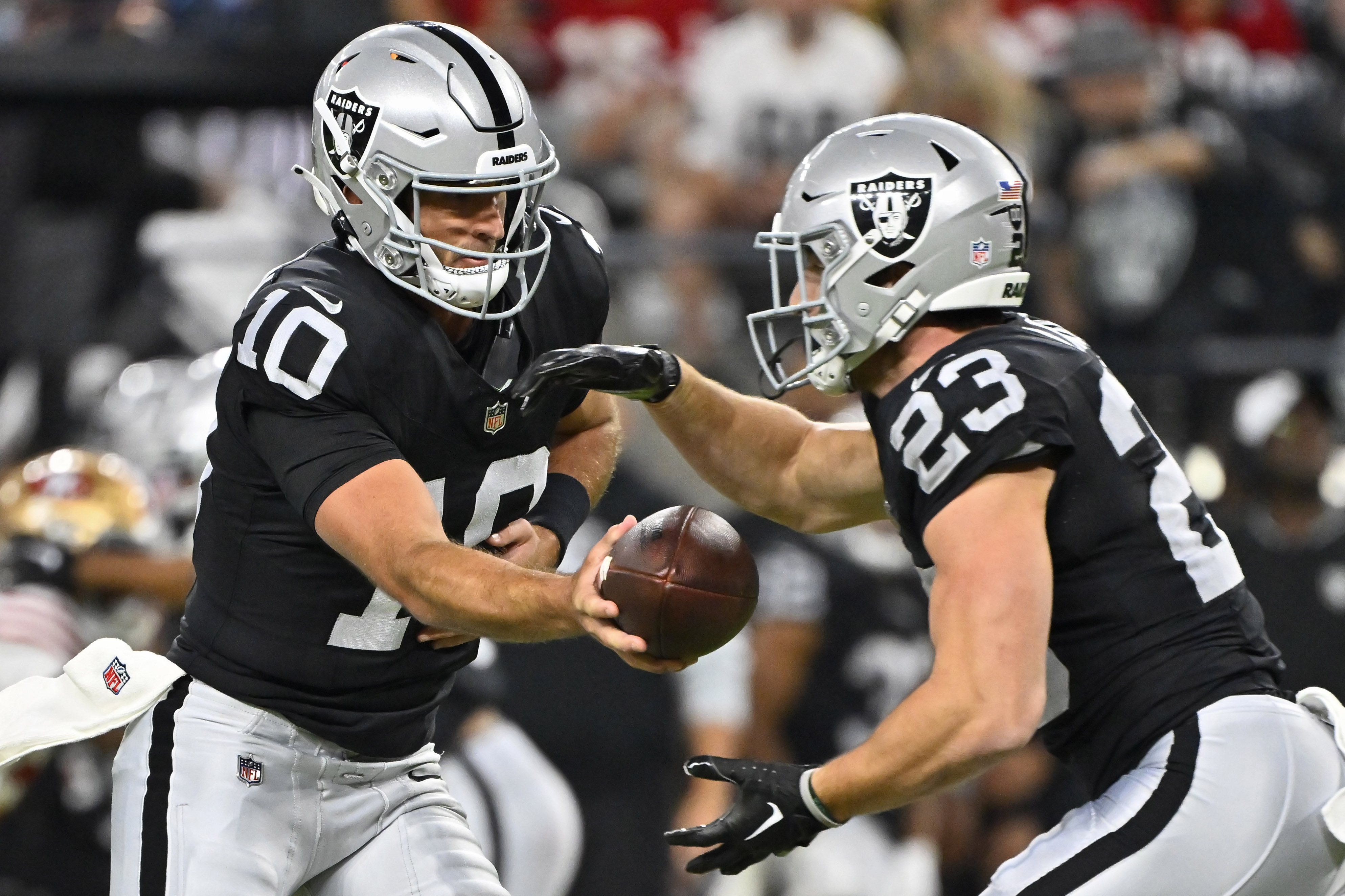 Las Vegas Raiders quarterback Nathan Peterman (10) hands off the ball to running back Dylan Laube (23) against the San Francisco 49ers during the first half of an NFL preseason football game, Friday, Aug. 23, 2024, in Las Vegas. 