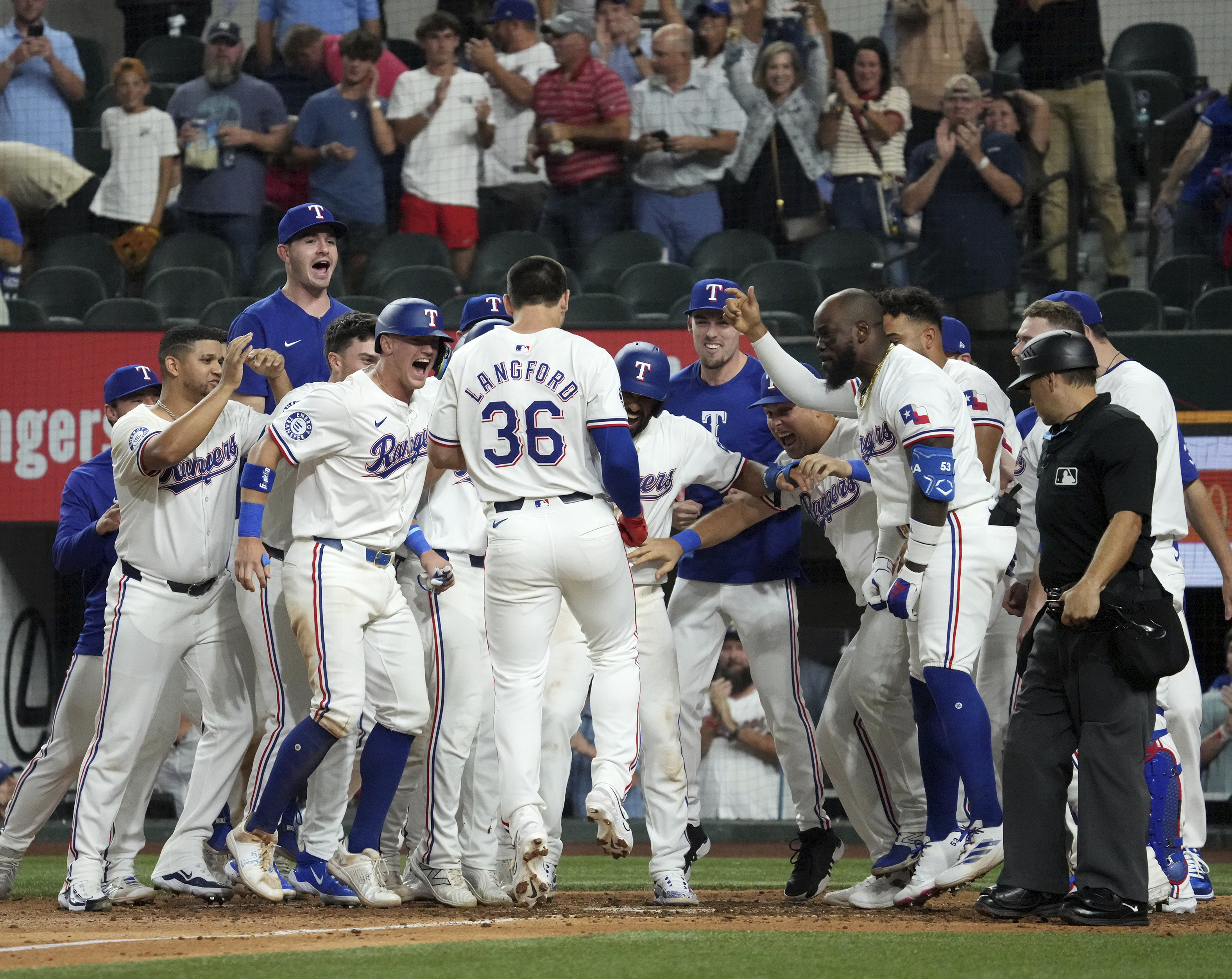 Texas Rangers' Wyatt Langford (36) is greeted at home plate after hitting a walk-off grand slam off of New York Yankees relief pitcher Clay Holmes during the ninth inning of a baseball game Tuesday, Sept. 3, 2024, in Arlington, Texas. Leody Taveras, Josh Smith and Marcus Semien scored on the play. 
