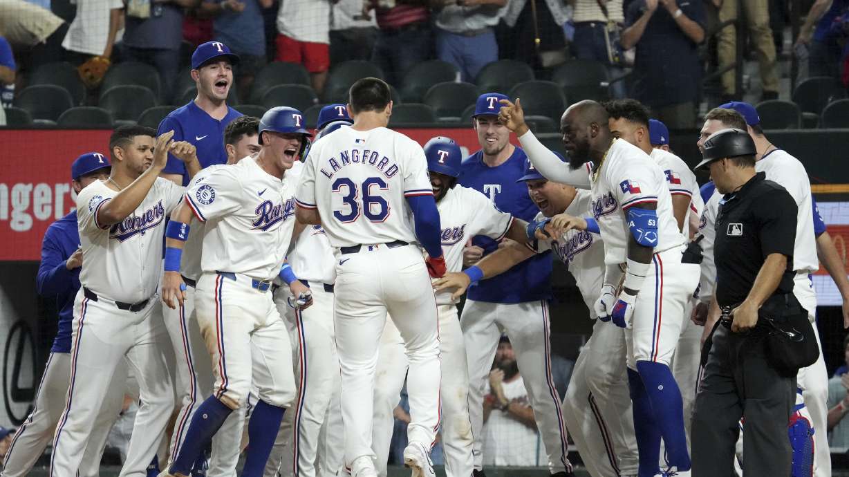Texas Rangers' Wyatt Langford (36) is greeted at home plate after hitting a walk-off grand slam off of New York Yankees relief pitcher Clay Holmes during the ninth inning of a baseball game Tuesday, Sept. 3, 2024, in Arlington, Texas. Leody Taveras, Josh Smith and Marcus Semien scored on the play.