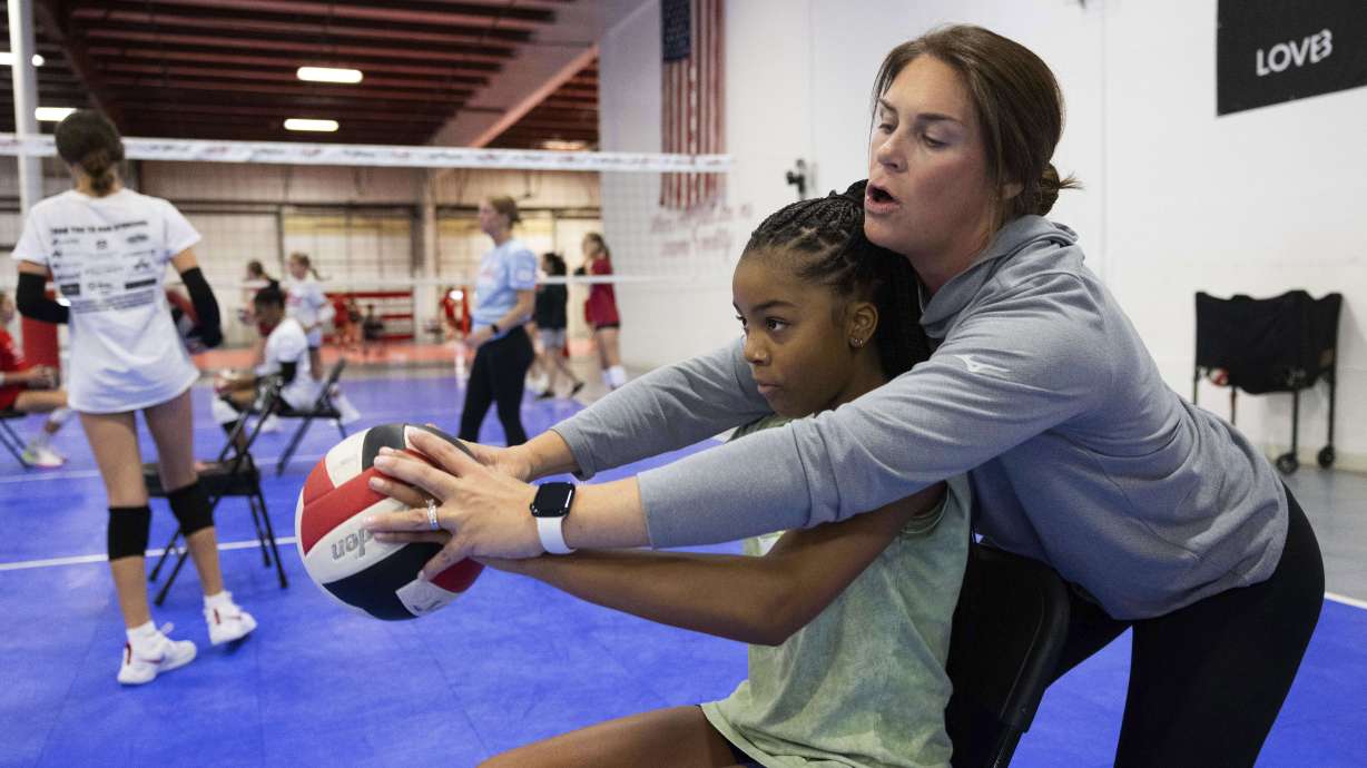 Premier Nebraska Volleyball club director Shannon Smolinski, right, guides Jamya Smith, 12, through a setting drill during practice Monday, Aug. 19, 2024, in Omaha, Neb.