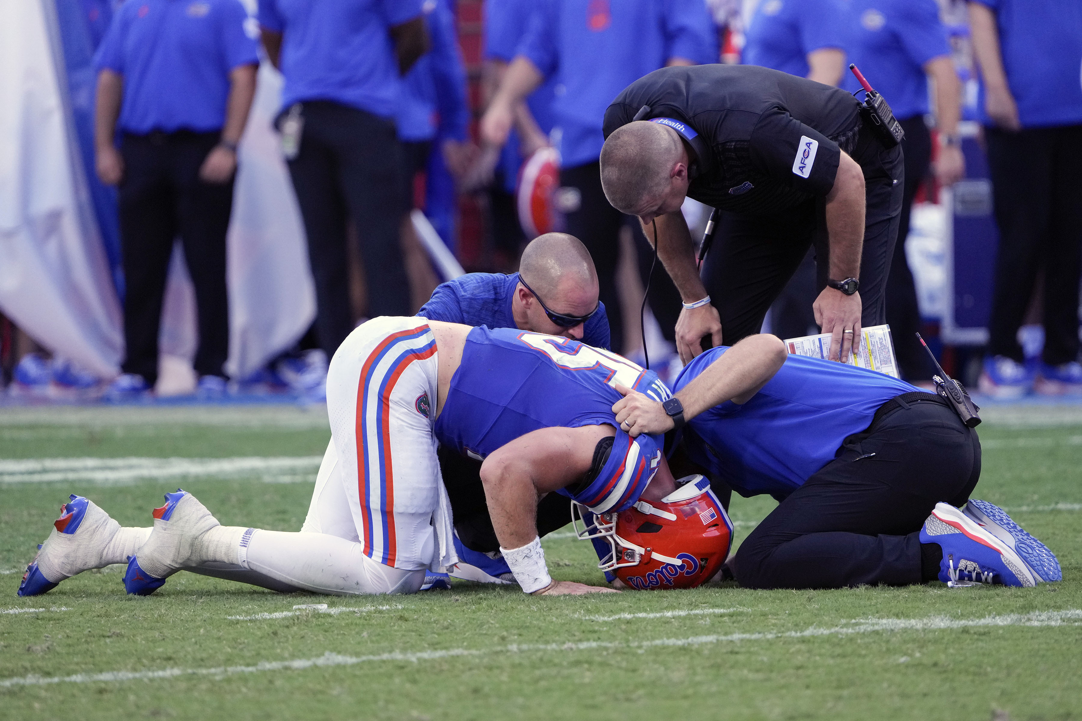 Florida quarterback Graham Mertz, front left, is looked at by head coach Billy Napier, top right, and other team personnel after he was injured during the second half of an NCAA college football game against Miami, Saturday, Aug. 31, 2024, in Gainesville, Fla. 