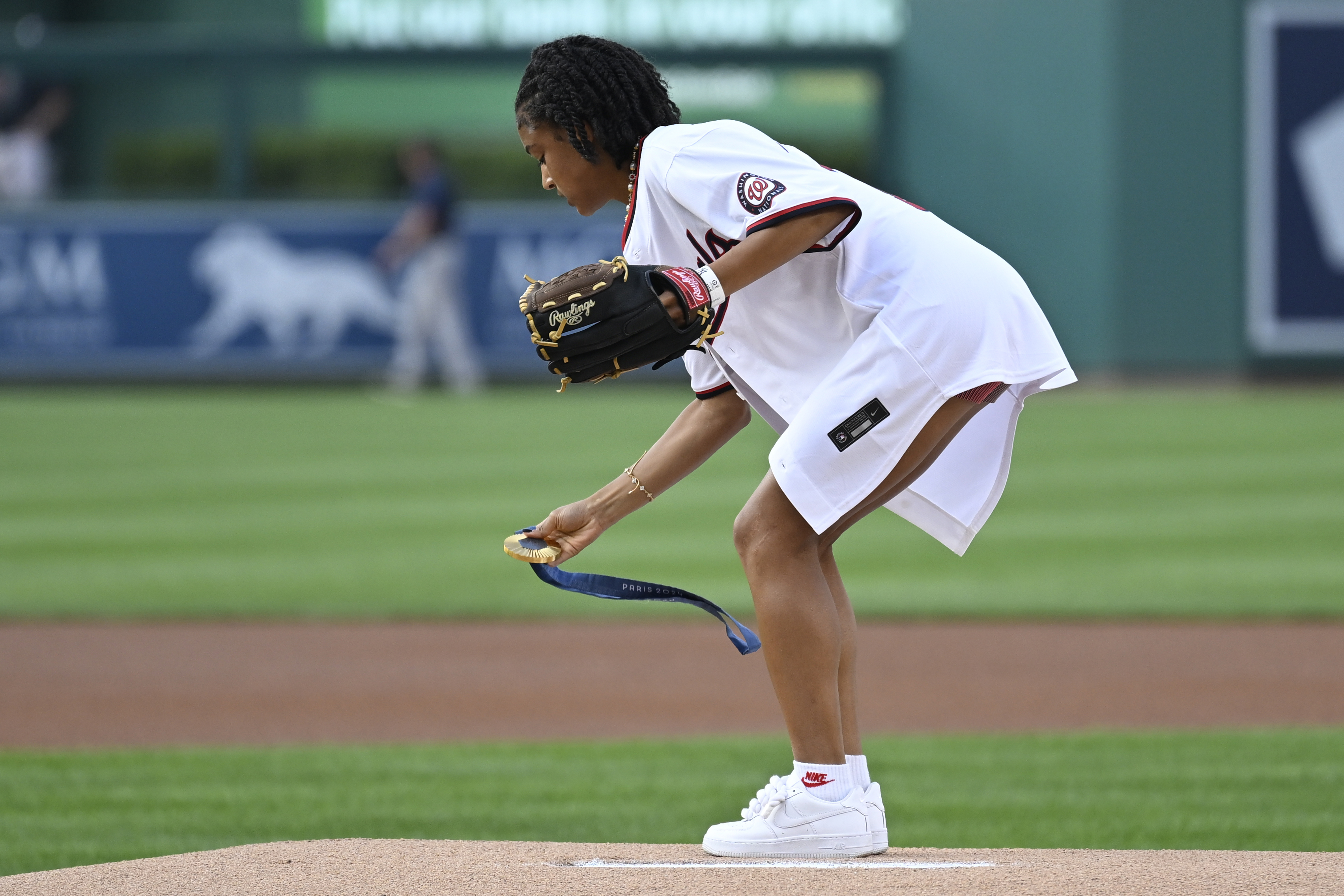 U.S. Olympic women's soccer team member Croix Bethune lays down her gold medal from the 2024 Paris Olympics on the pitcher's mound so she can throw the opening pitch before a baseball game between the Washington Nationals and New York Yankees, Wednesday, Aug. 28, 2024, in Washington. 