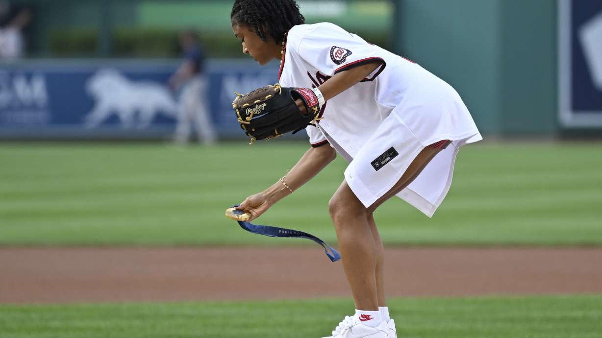 U.S. Olympic women's soccer team member Croix Bethune lays down her gold medal from the 2024 Paris Olympics on the pitcher's mound so she can throw the opening pitch before a baseball game between the Washington Nationals and New York Yankees, Wednesday, Aug. 28, 2024, in Washington.