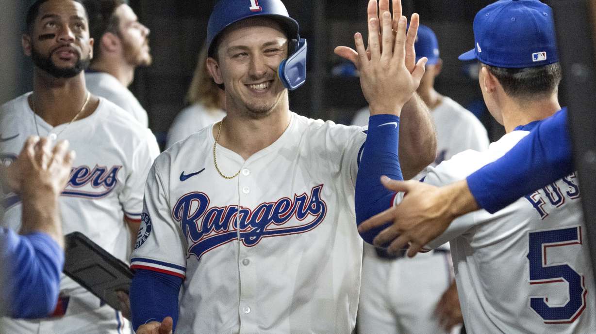 Texas Rangers' Wyatt Langford is congratulated in the dugout by Justin Foscue after scoring on a single by Nathaniel Lowe during the fourth inning of a baseball game against the New York Yankees, Wednesday, Sept. 4, 2024, in Arlington, Texas.