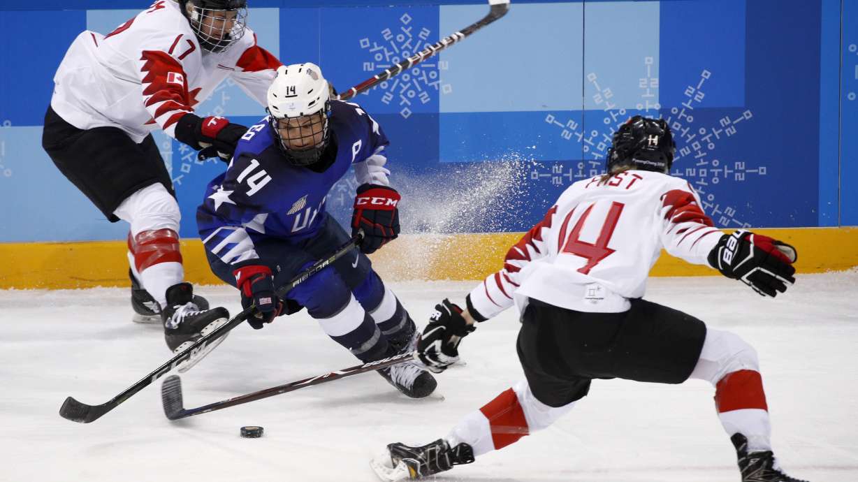 FILE - Brianna Decker (14), of the United States, skates with the puck away from Bailey Bram (17) and Renata Fast (14), of Canada, during the first period of the women's gold medal hockey game at the 2018 Winter Olympics in Gangneung, South Korea, Thursday, Feb. 22, 2018.