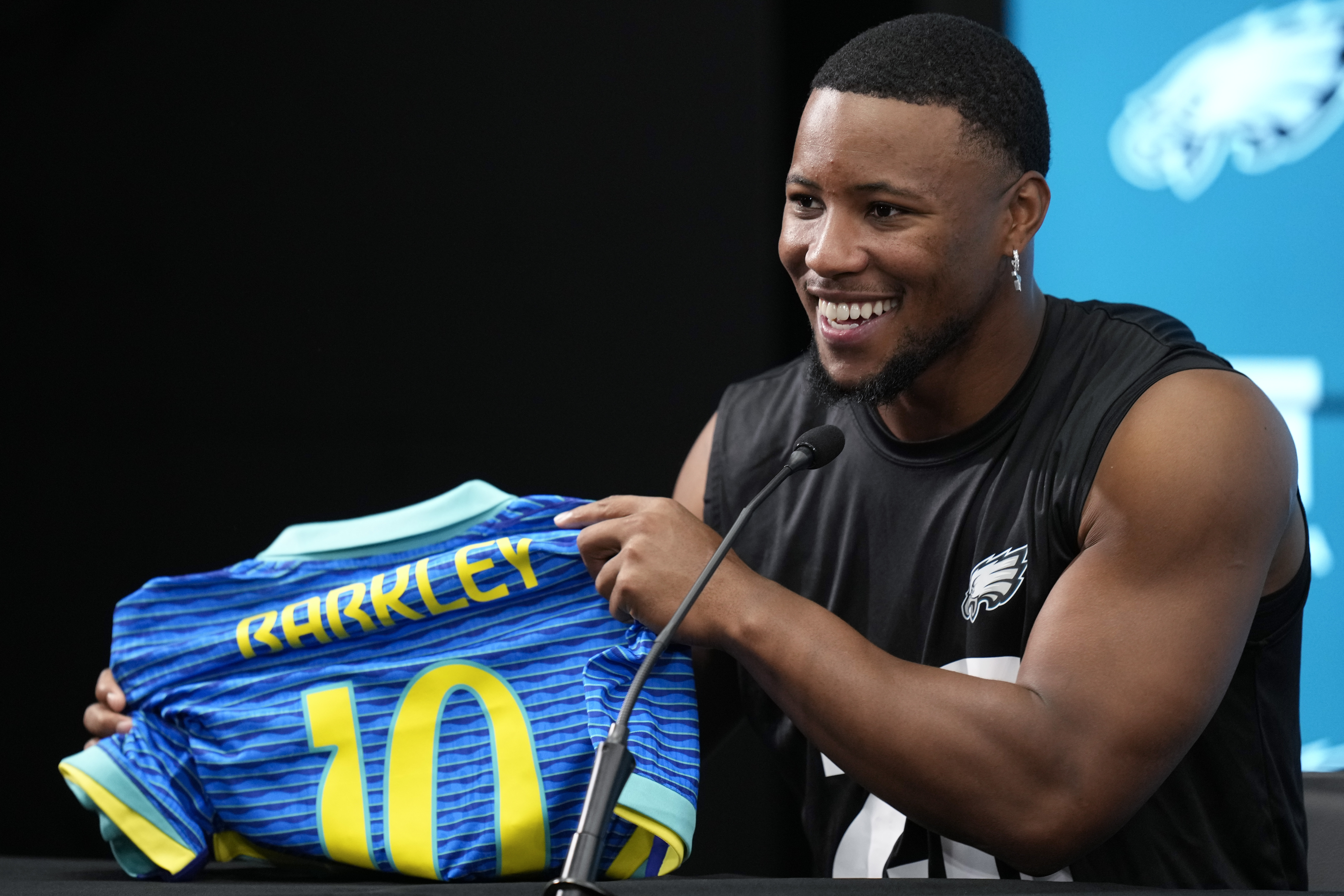 Philadelphia Eagles Saquon Barkley holds up a Brazilian national soccer jersey with his name on it, during a press conference ahead of a game against the Green Bay Packers at the Neo Quimica Arena in Sao Paulo, Thursday, Sept. 5, 2024. 