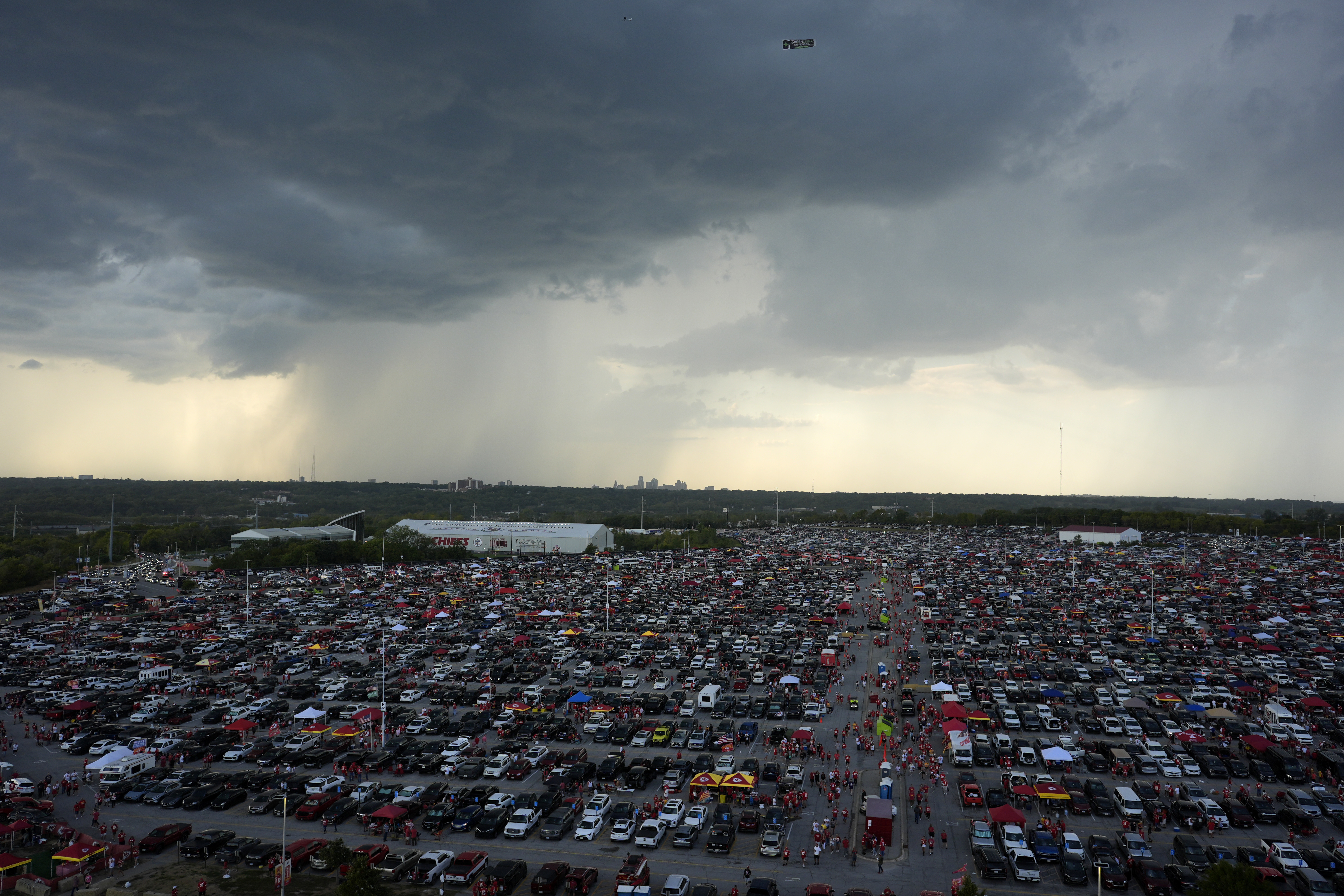 Clouds are seen in the distance as fans fill the parking lot outside Arrowhead Stadium before the start of an NFL football game between the Kansas City Chiefs and the Baltimore Ravens Thursday, Sept. 5, 2024, in Kansas City, Mo. 