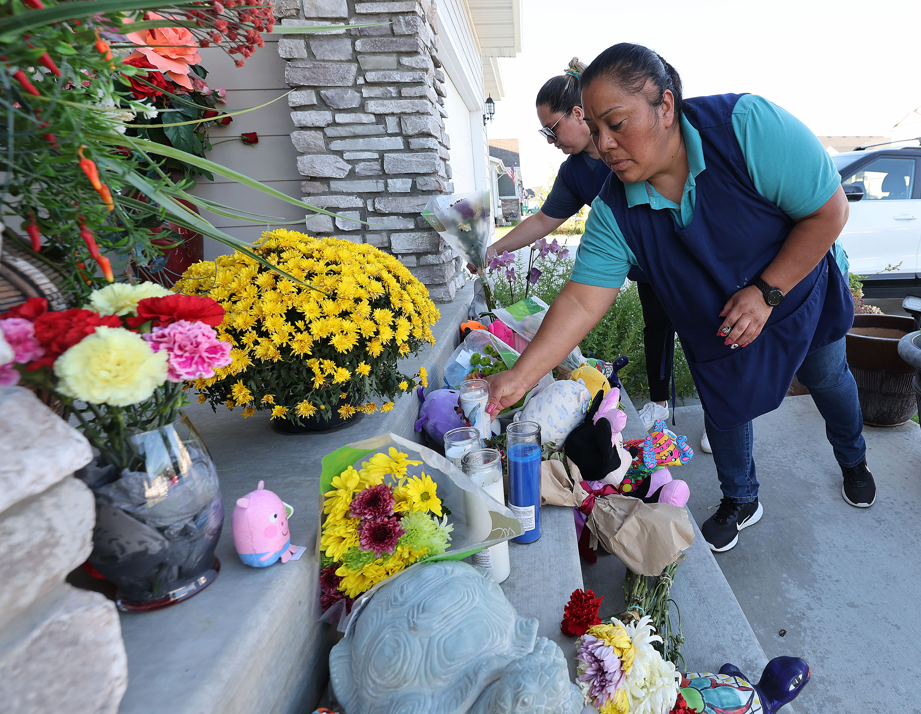 Joeana Solaria and Albina Sanchez place flowers and candles at a home in West Haven on Thursday. Police on Friday said the mother who lived there shot and killed her three children before taking her own life earlier this week.