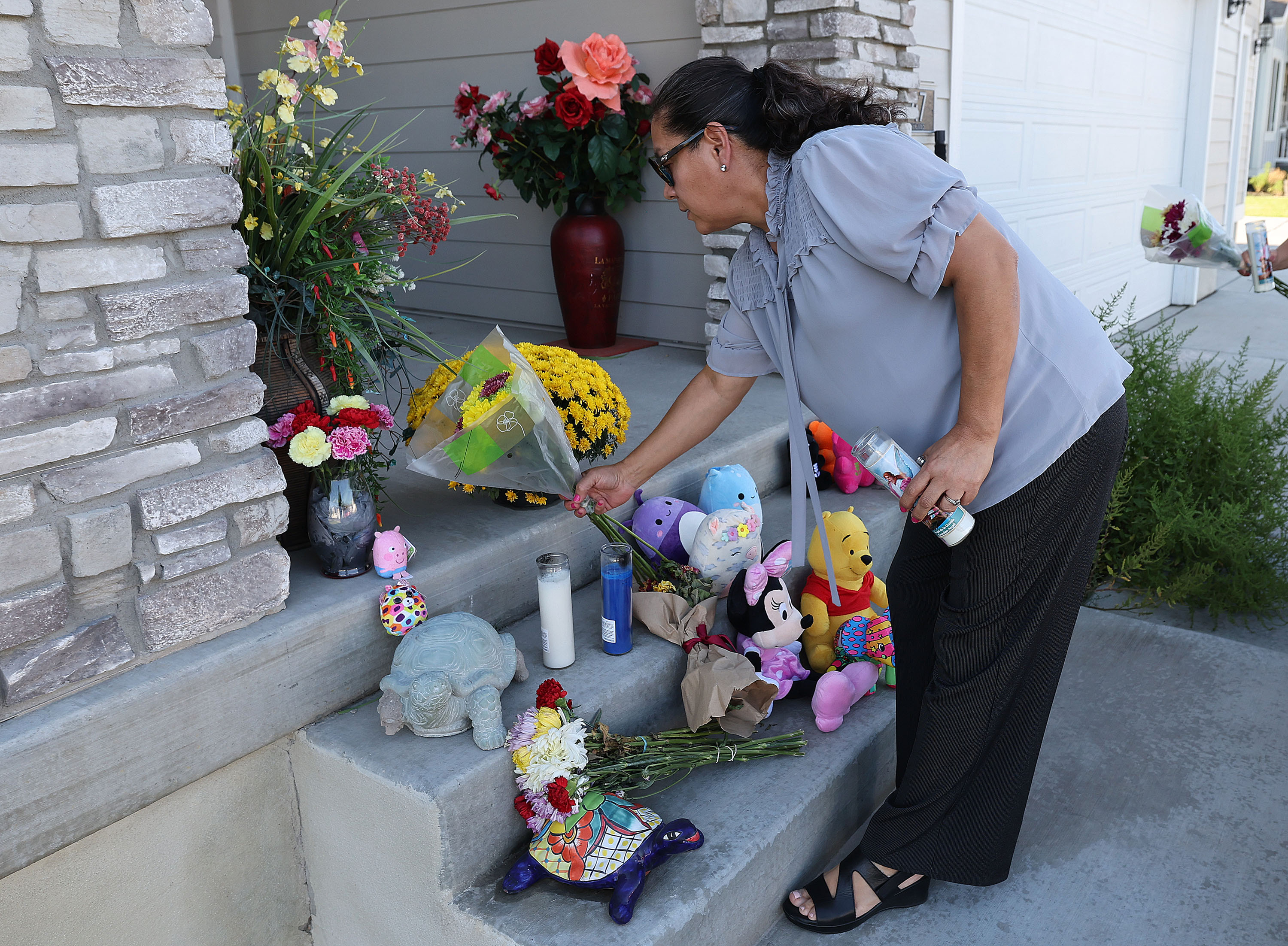 Maria Orozco places flowers along with other well wishers items at the home in West Haven on Sept. 5, where three children and their mother were shot and killed.