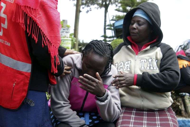Kenya Red Cross personnel and relatives try to comfort a woman reacting near a burned-out dormitory, following a fire at the Hillside Endarasha Primary in Nyeri, Kenya, Friday.