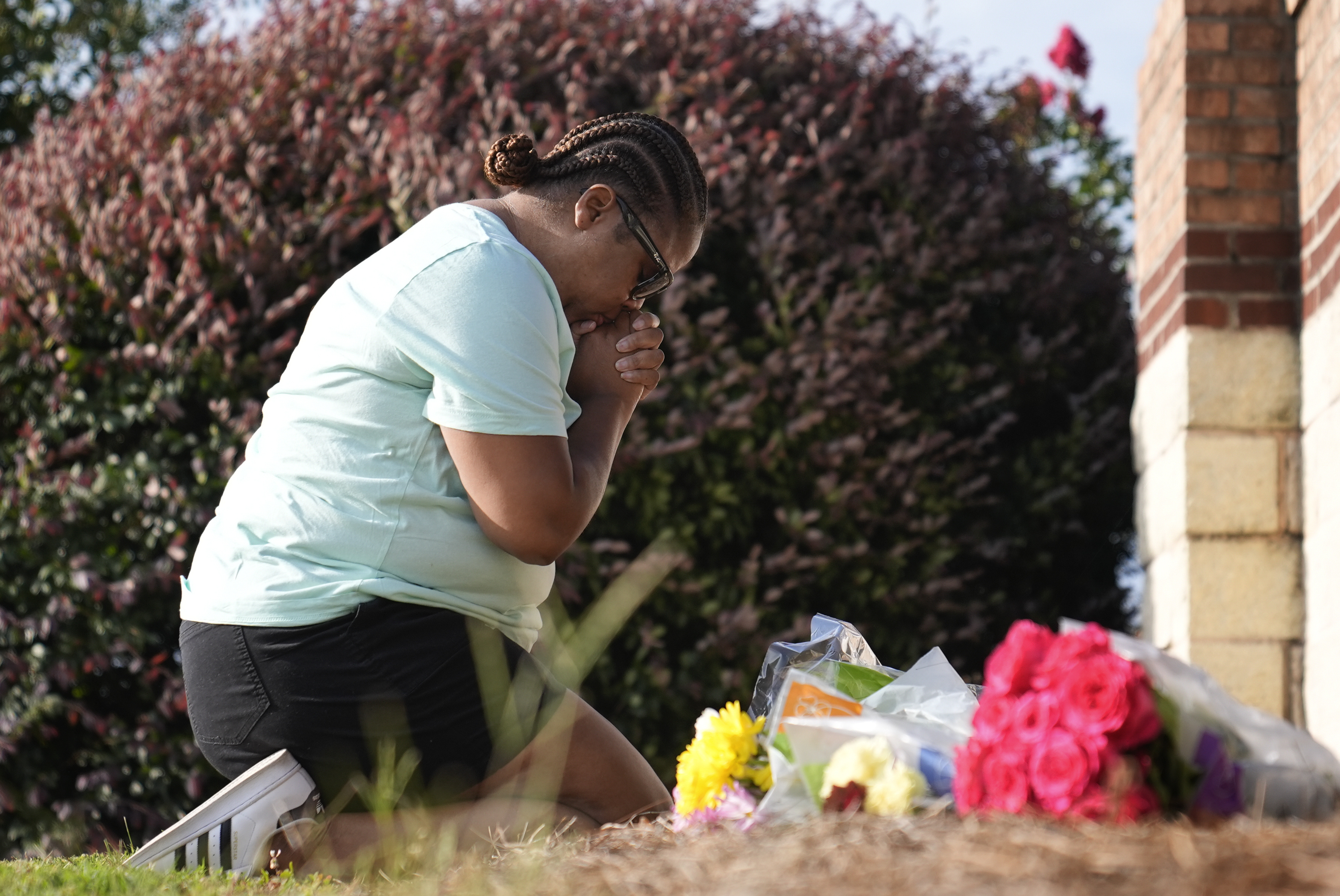 Linda Carter, of Grayson, Ga., kneels near Apalachee High School to place flowers as she mourns for the slain students and teachers on Sept. 5, in Winder, Ga.