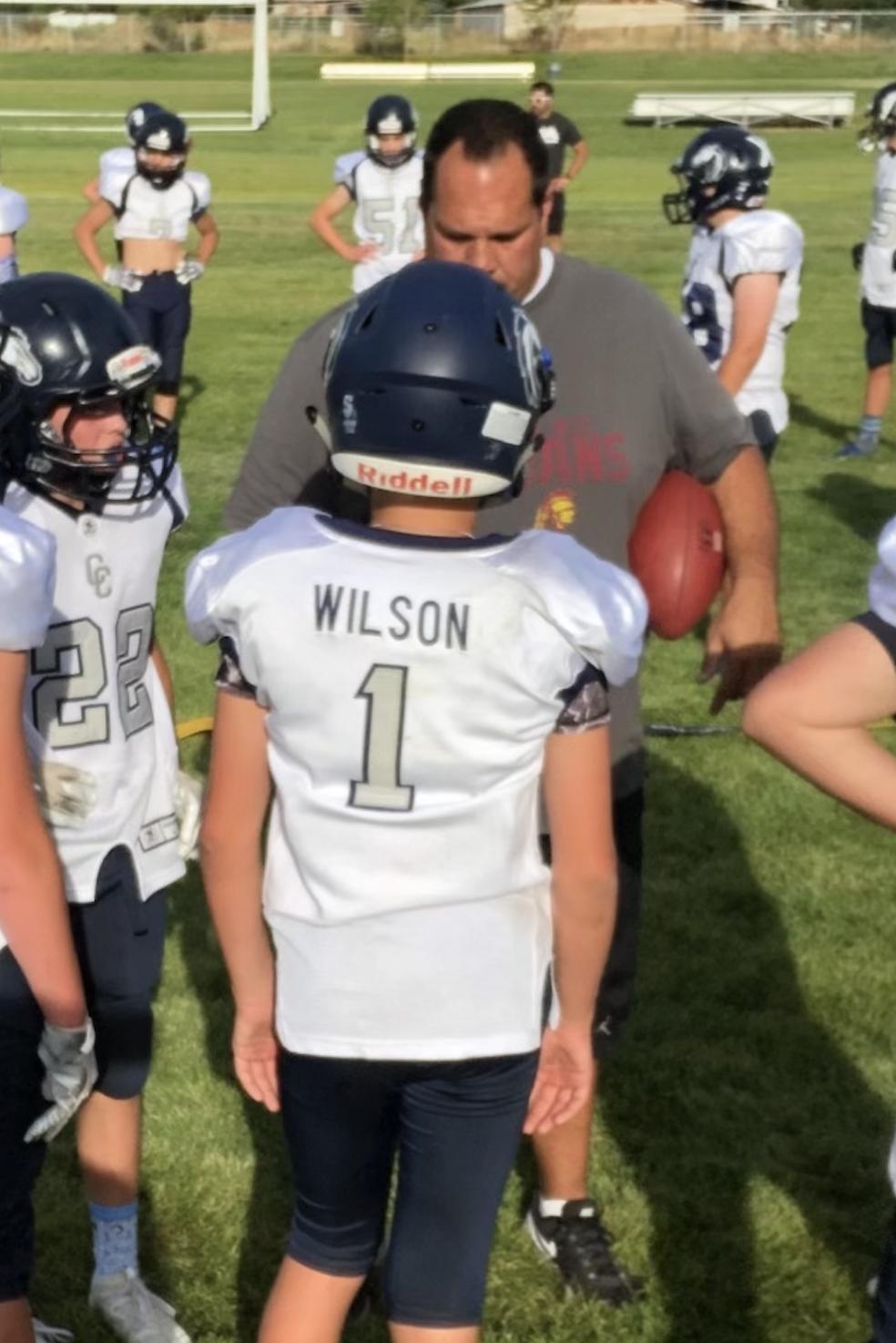 Mike Wilson speaks to his son, Isaac Wilson, during a youth football game.