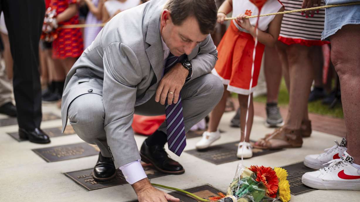 Clemson head coach Dabo Swinney stops to pay his respects to former Clemson player Diondre Overton while walking to the stadium before an NCAA college football game against Appalachian State, Saturday, Sept. 7, 2024, in Clemson, S.C.
